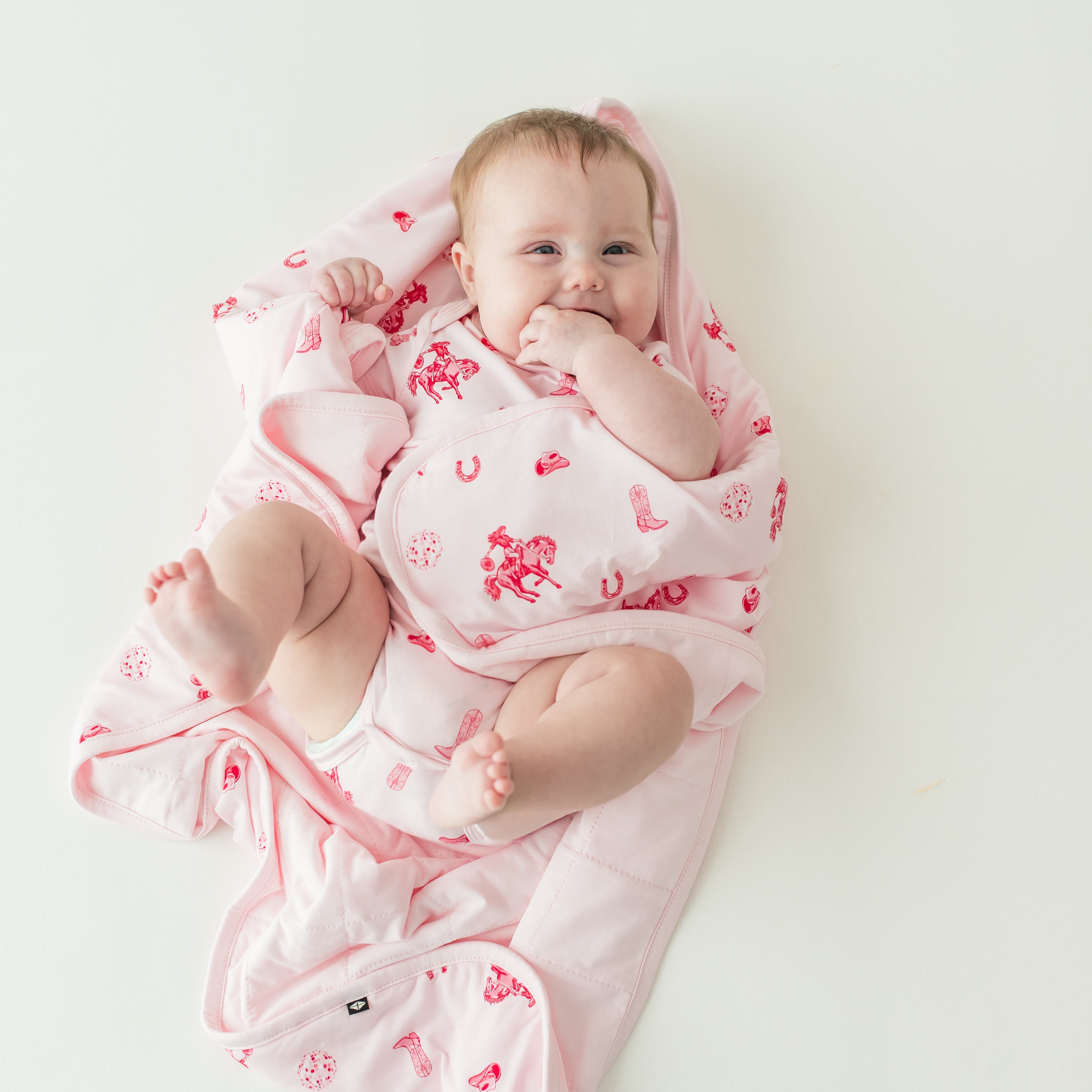 Infant girl laying wrapped in a Baby Blanket in Disco Cowgirl wearing a matching short sleeve bodysuit