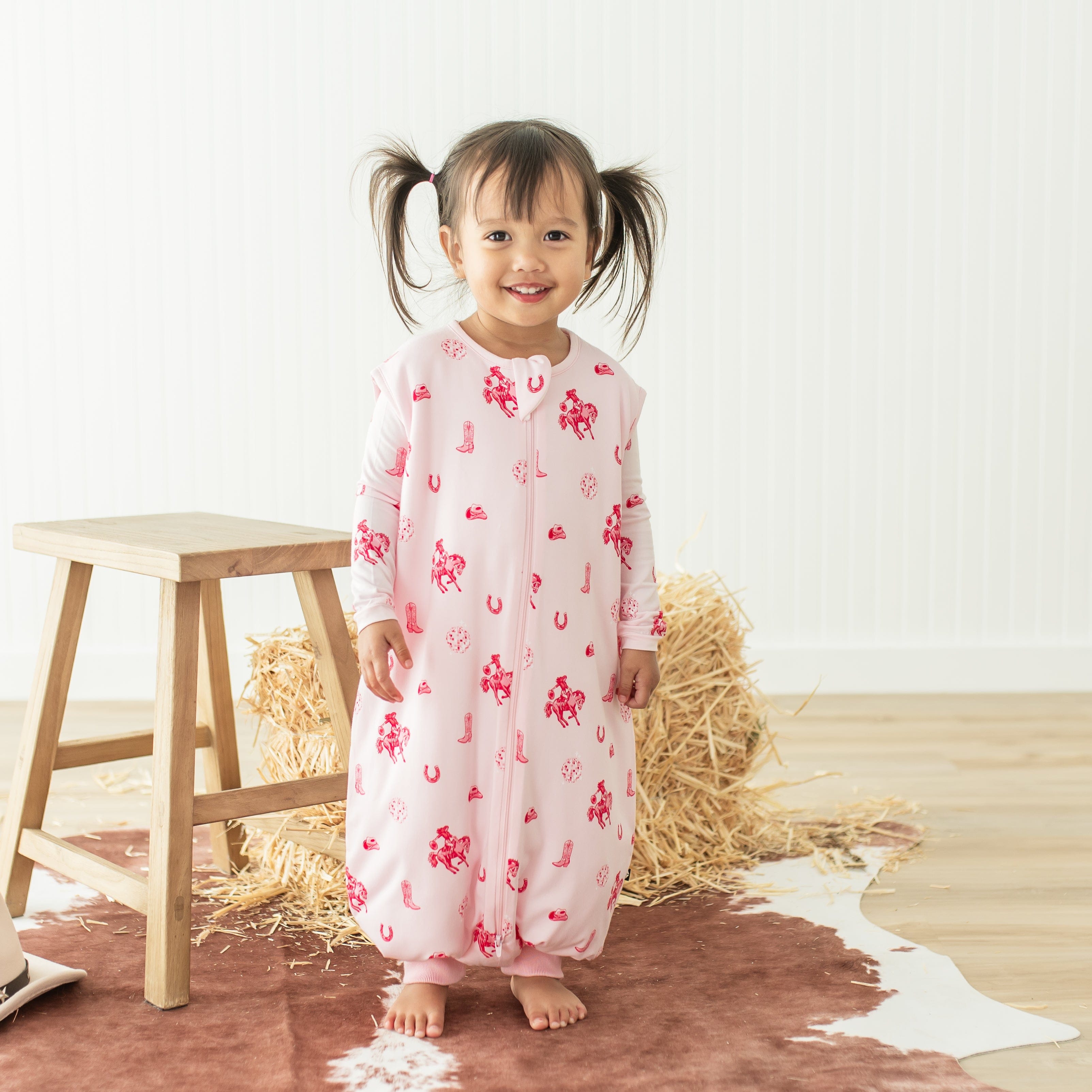 Young girl standing wearing the Sleep Bag Walker in Disco Cowgirl 1.0 with the matching long sleeve toddler pajamas on underneath