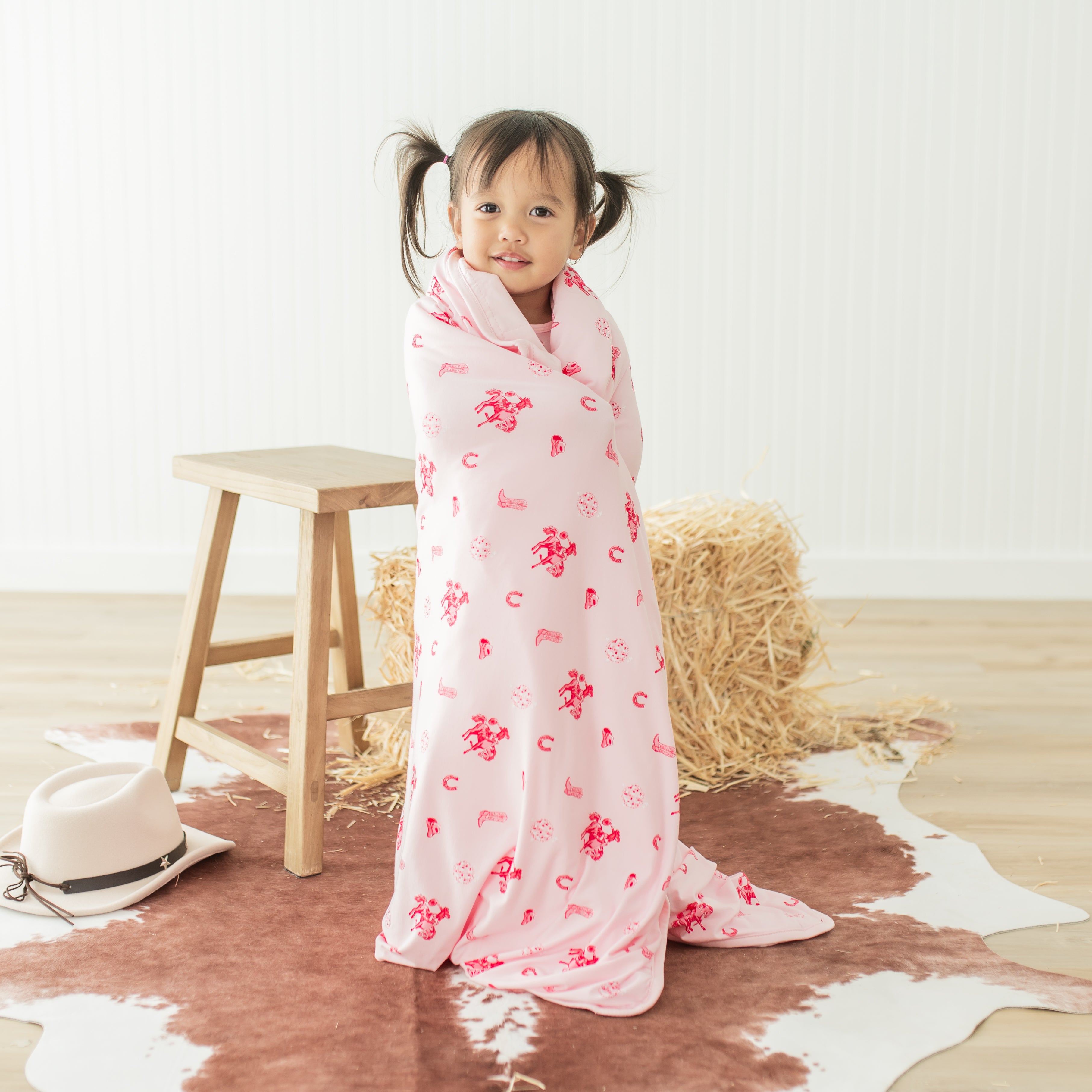 Young toddler standing with the Toddler Blanket in Disco Cowgirl 1.0 wrapped around her