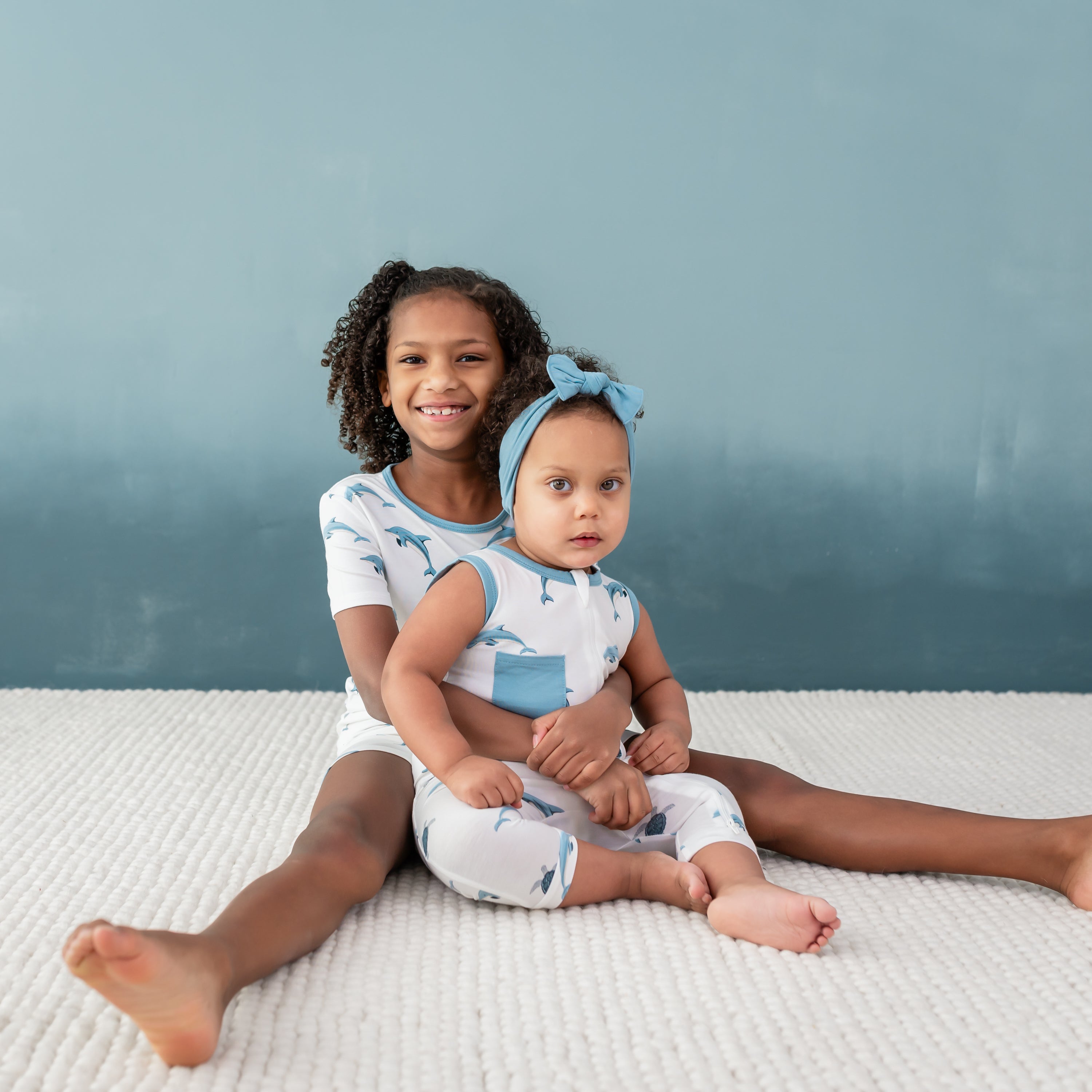 Siblings wearing matching Kyte Baby outfits in dophin print