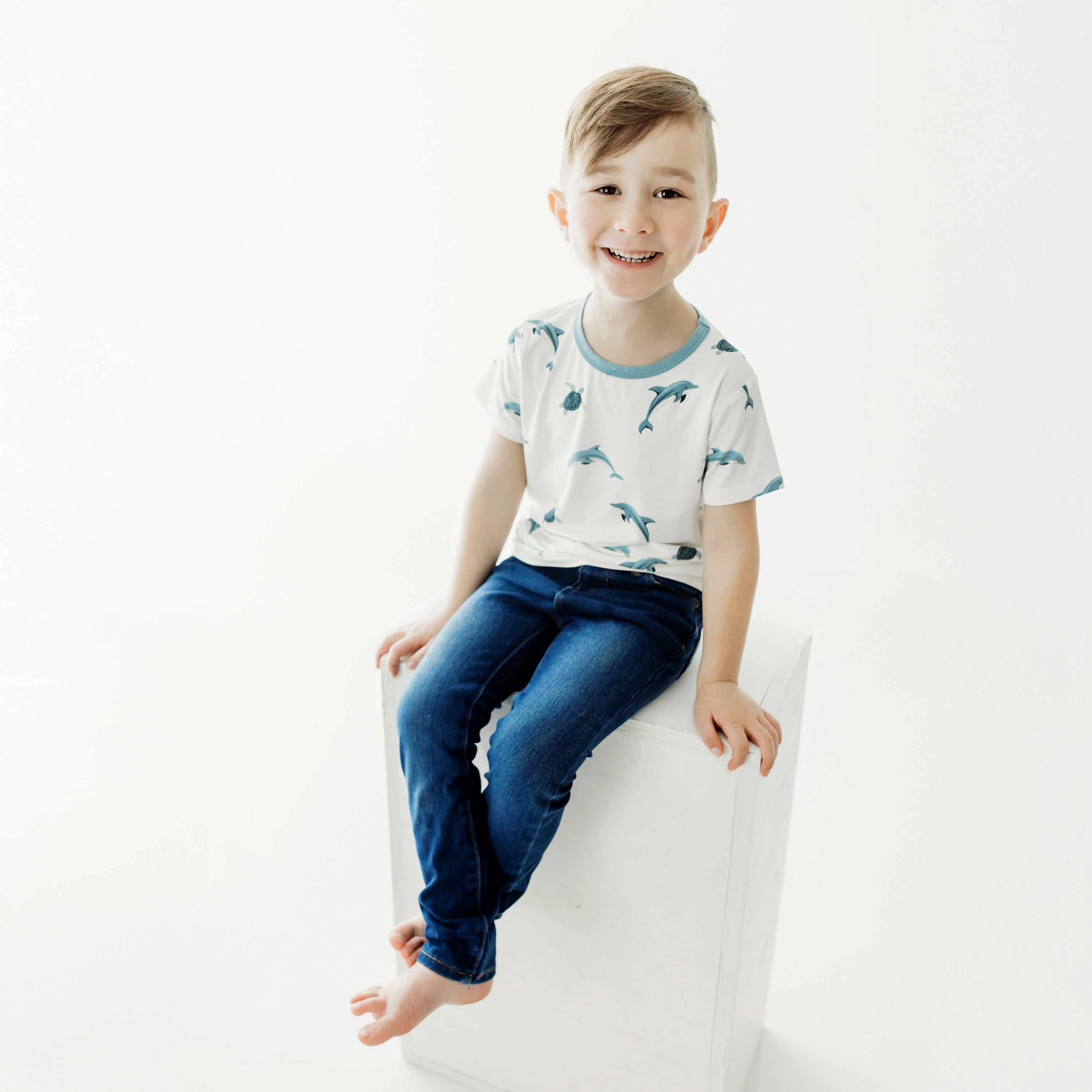 child sitting modeling basic tee in dolphin