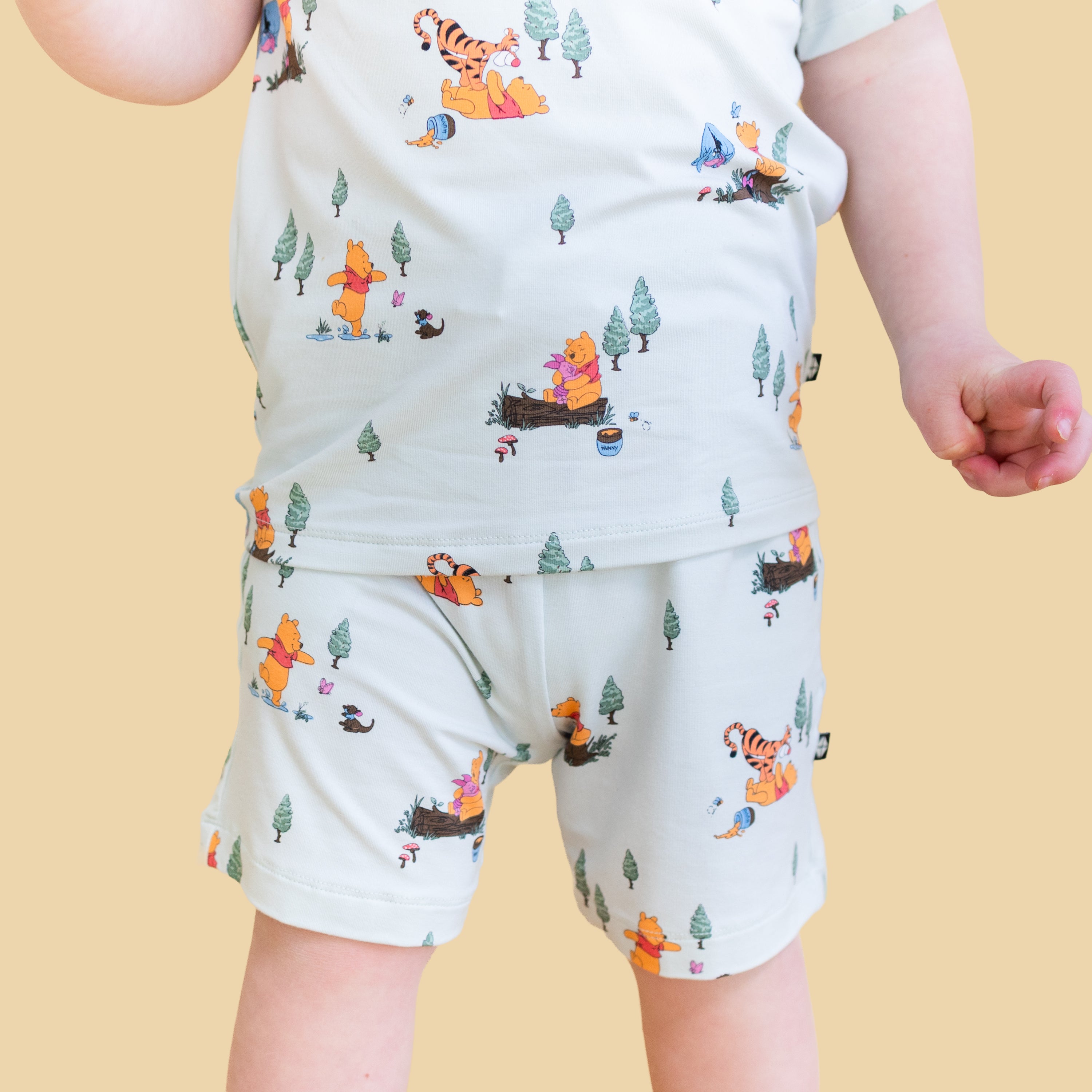Close up of young boy wearing the Drawstring Short in Winnie the Pooh Hundred Acre Wood paired with a matching shirt