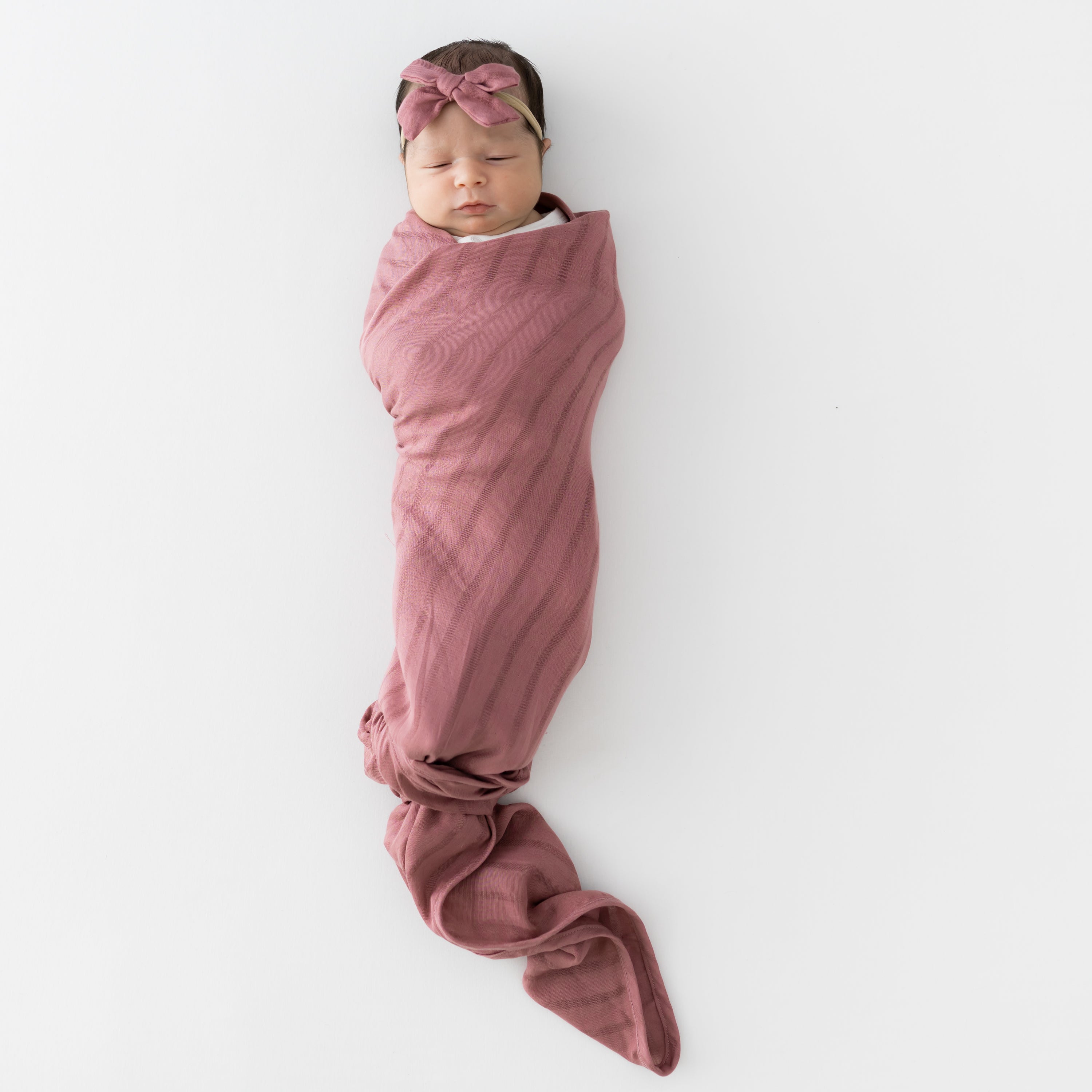 Baby swaddled in Bamboo Muslin Swaddle Blanket in Dusty Rose