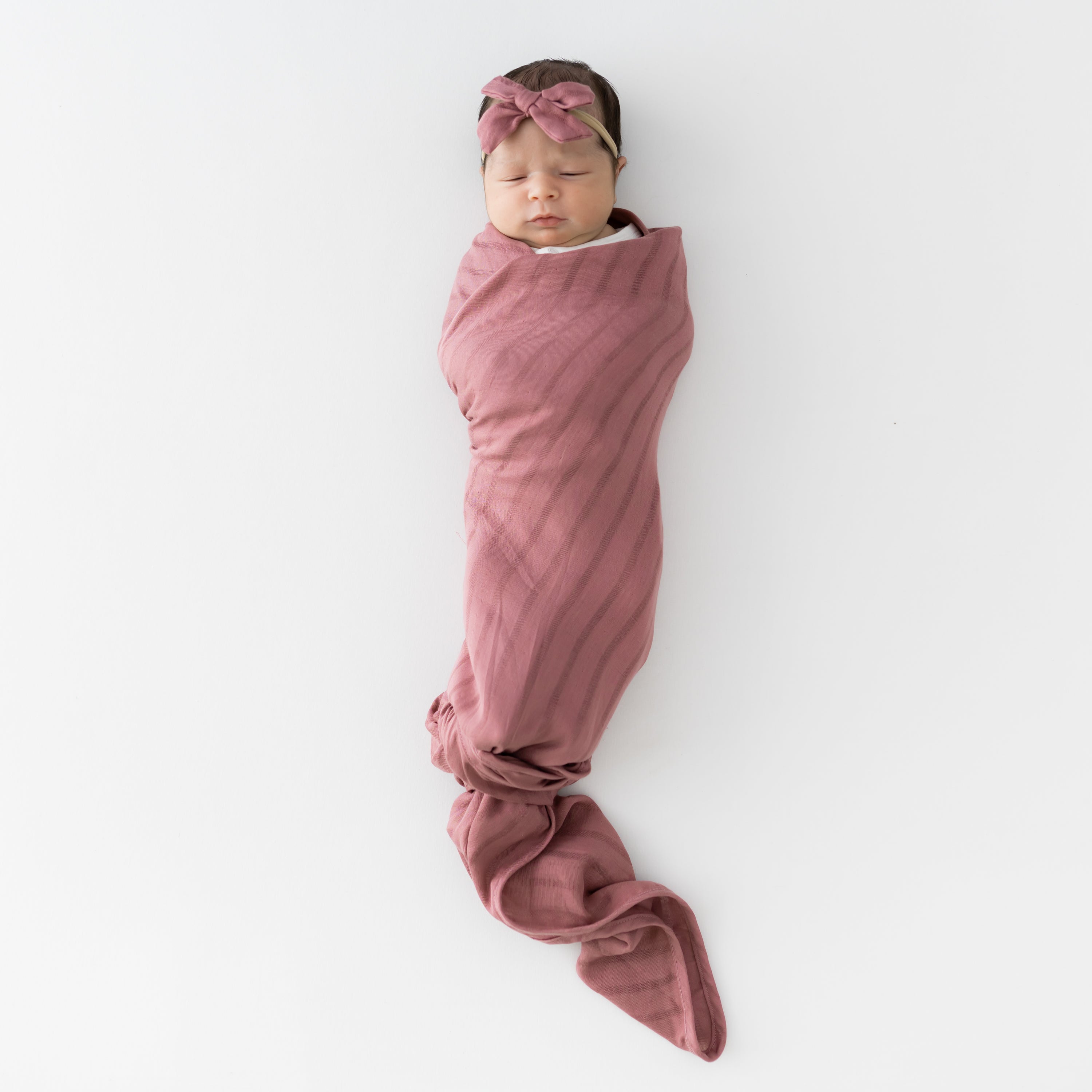 Baby wrapped in Bamboo Muslin Swaddler Blanket in Dusty Rose