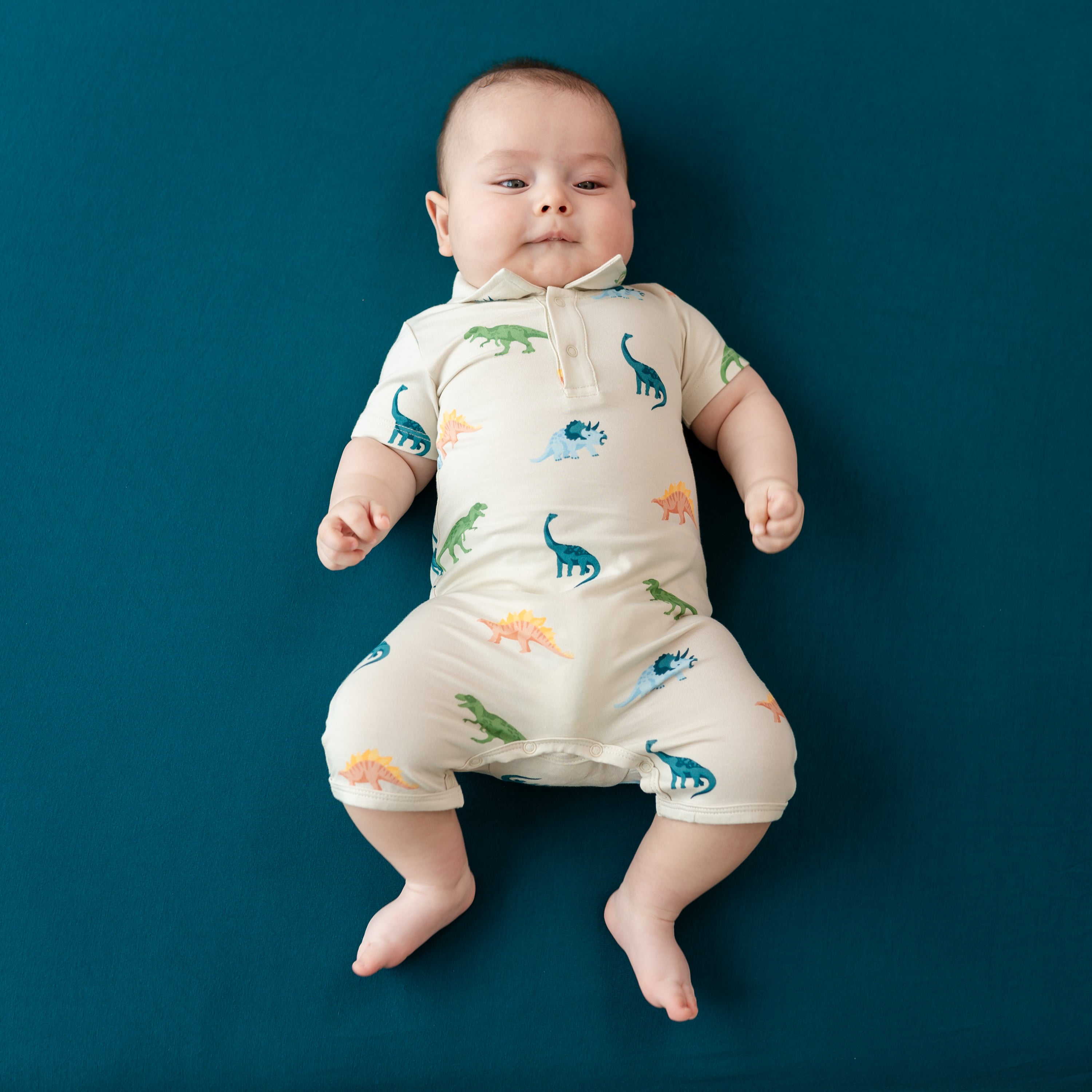 Baby wearing Dinosaur Polo Shortall in Ecru Roar