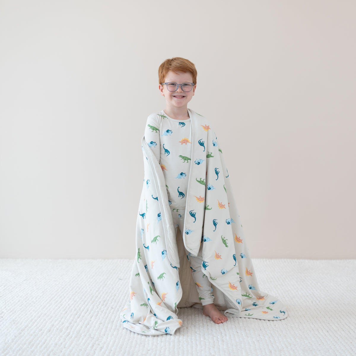 Smiling Child in Ecru Roar Pajamas wrapped in Youth Blanket in Ecru Roar 1.0