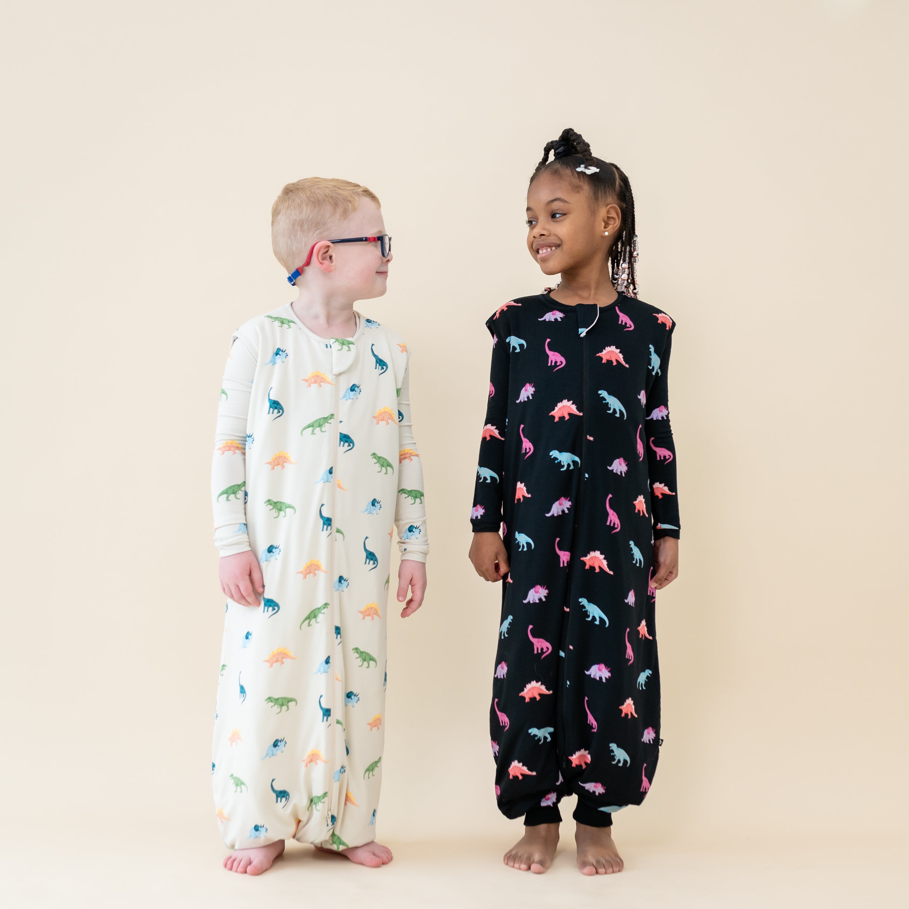 Two smiling children wearing 1.0 TOG Sleep Bag Walkers in Midnight and Ecru Roar