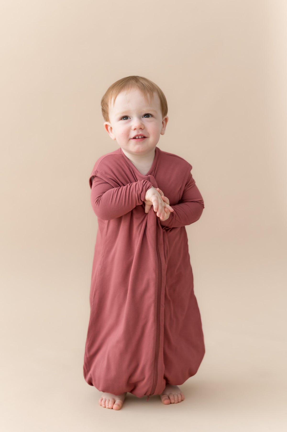 Child wearing Sleep Bag Walker in Ember 1.0 on a beige background