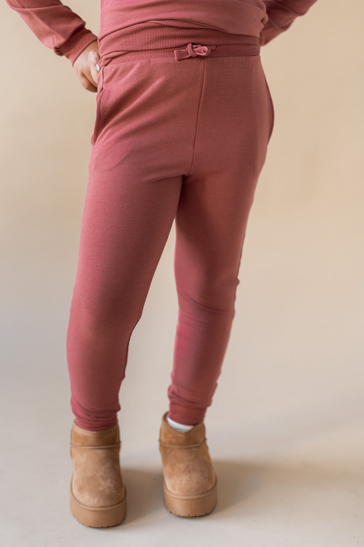 Modal wearing Jogger Pant in Ember color under similar color sweatshirt on a beige background