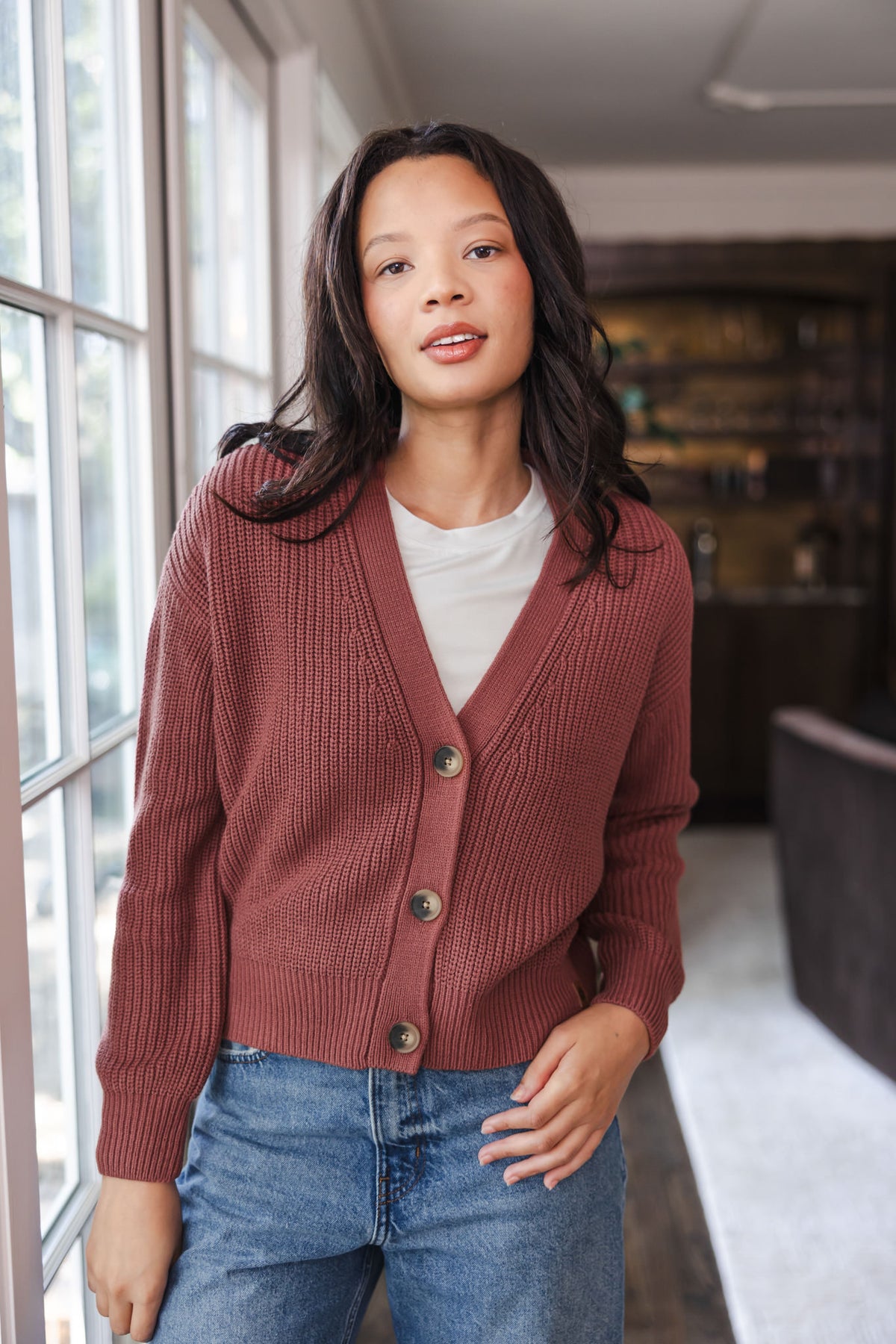 Modal wearing Chunky Knit Women's Cropped Cardigan In Ember over white T-shirt and blue jeans