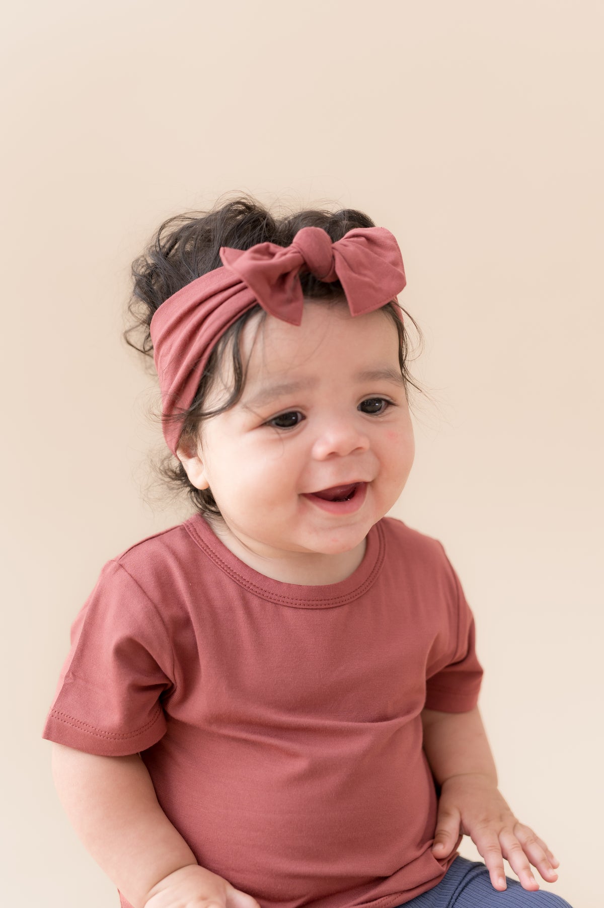 Child wearing Toddler Basic Tee in Ember with similar color knotted bow headband