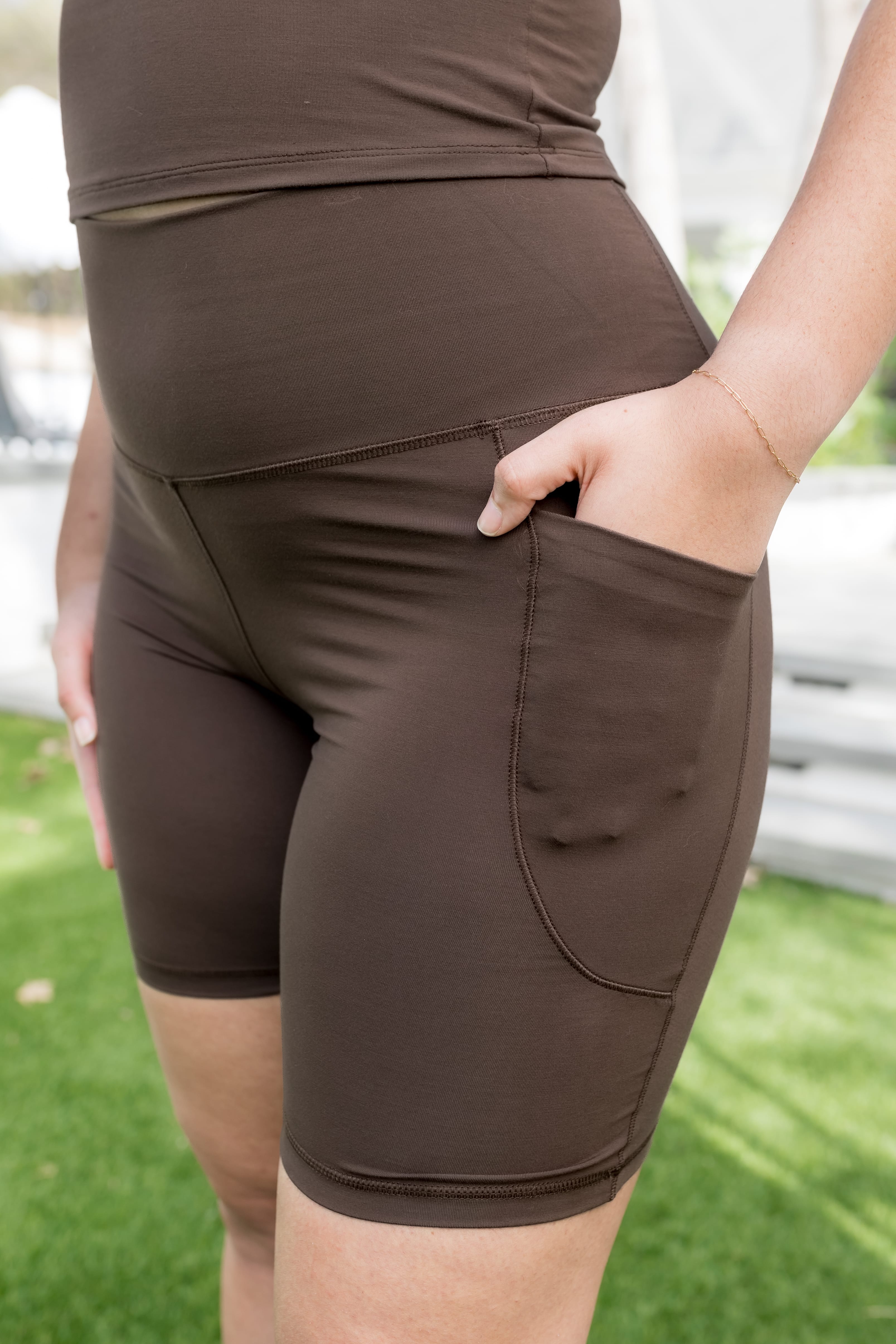 Female model wearing the Bamboo Flex High Rise Biker Short in Espresso with one hand in the side pocket