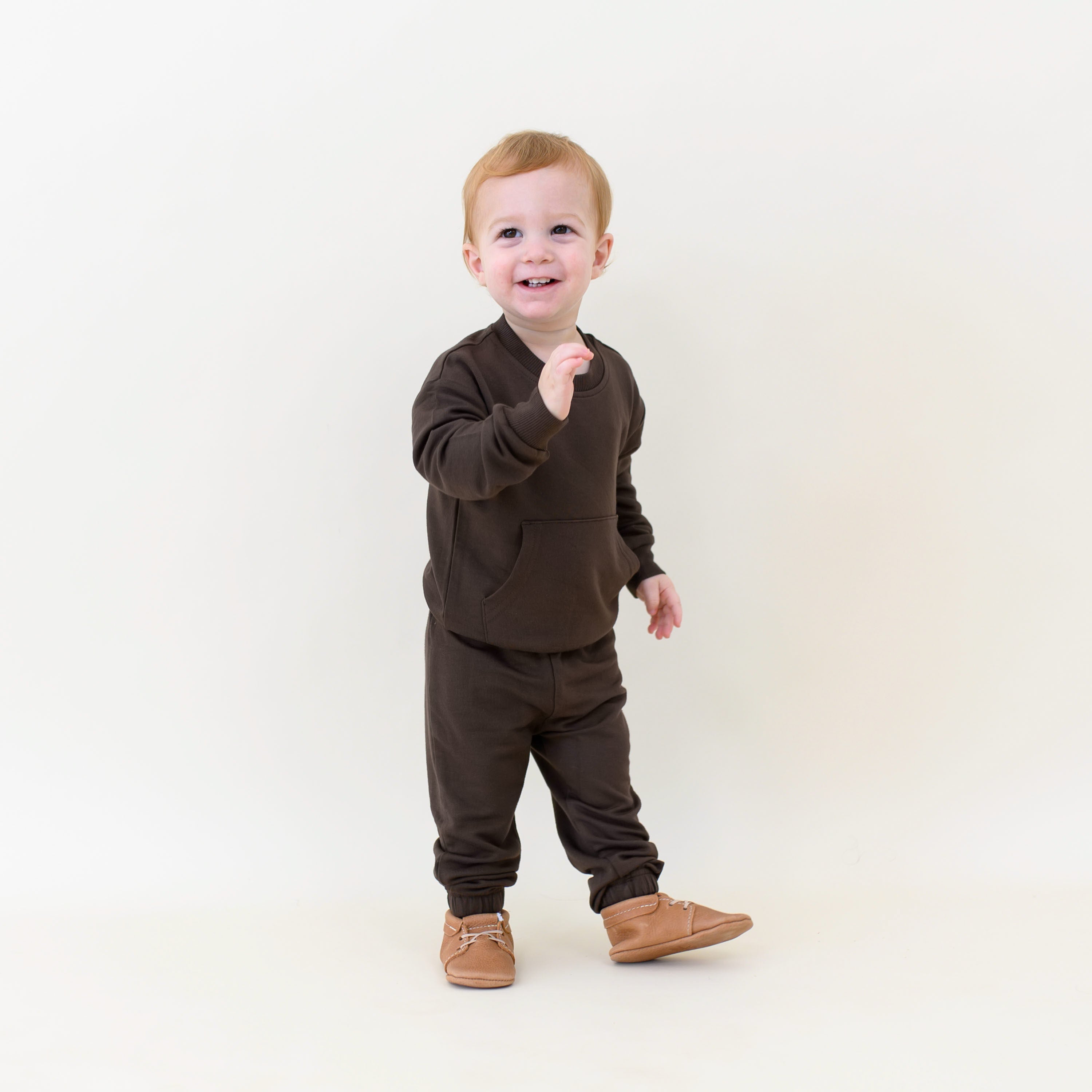 Smiling toddler walking wearing the French Terry Jogger Set in Espresso
