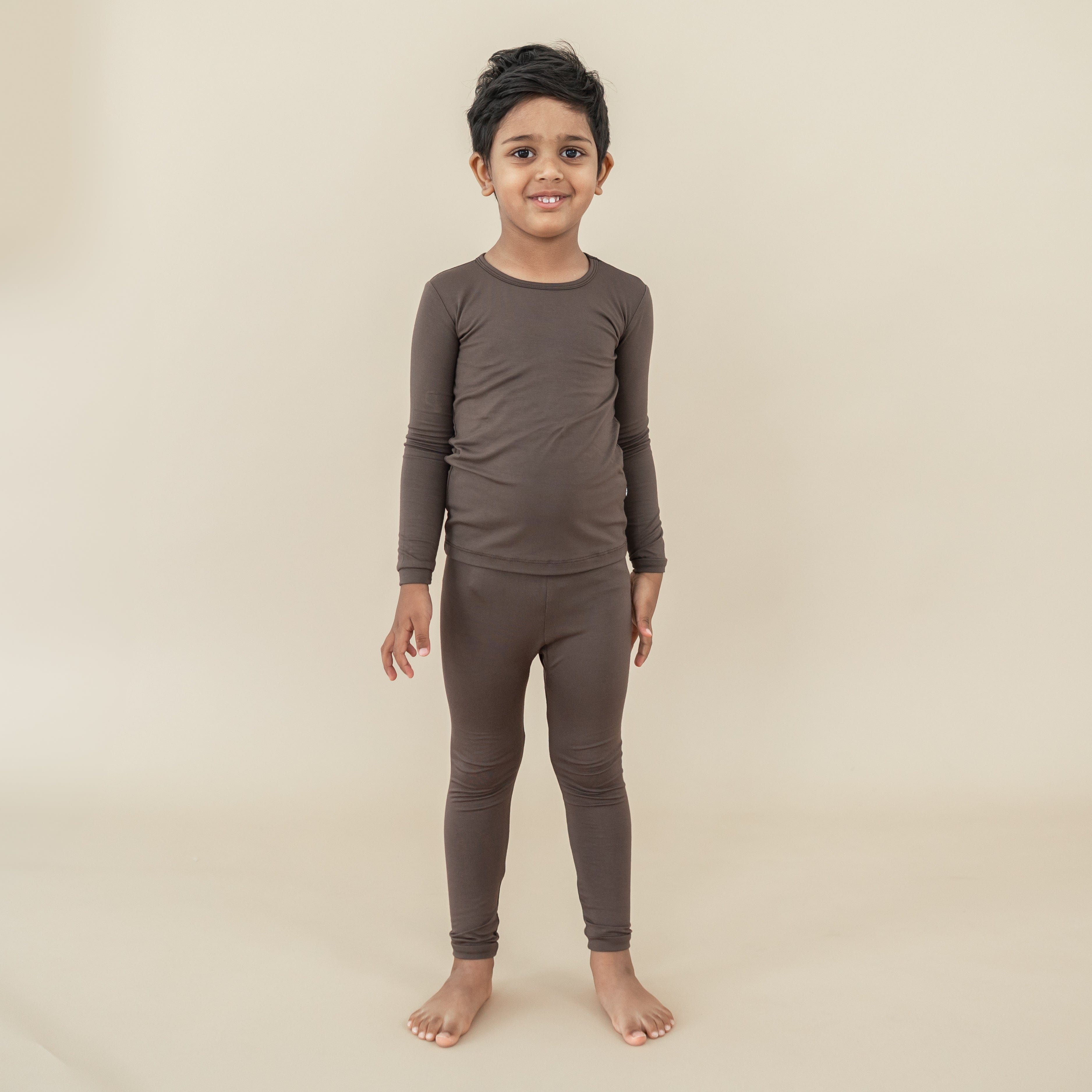 Boy model standing wearing the Long Sleeve Pajamas in Espresso