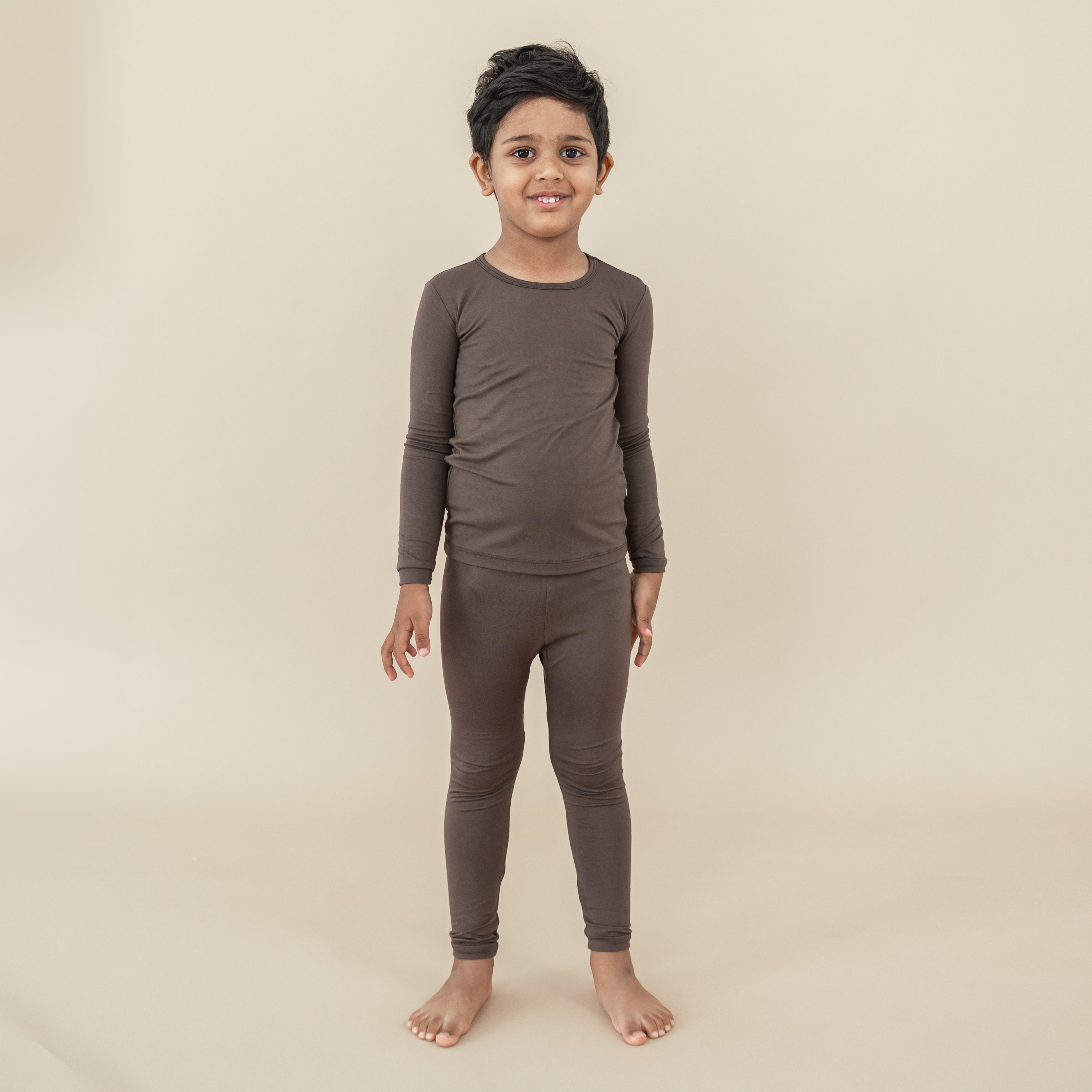 Boy model standing wearing the Long Sleeve Pajamas in Espresso