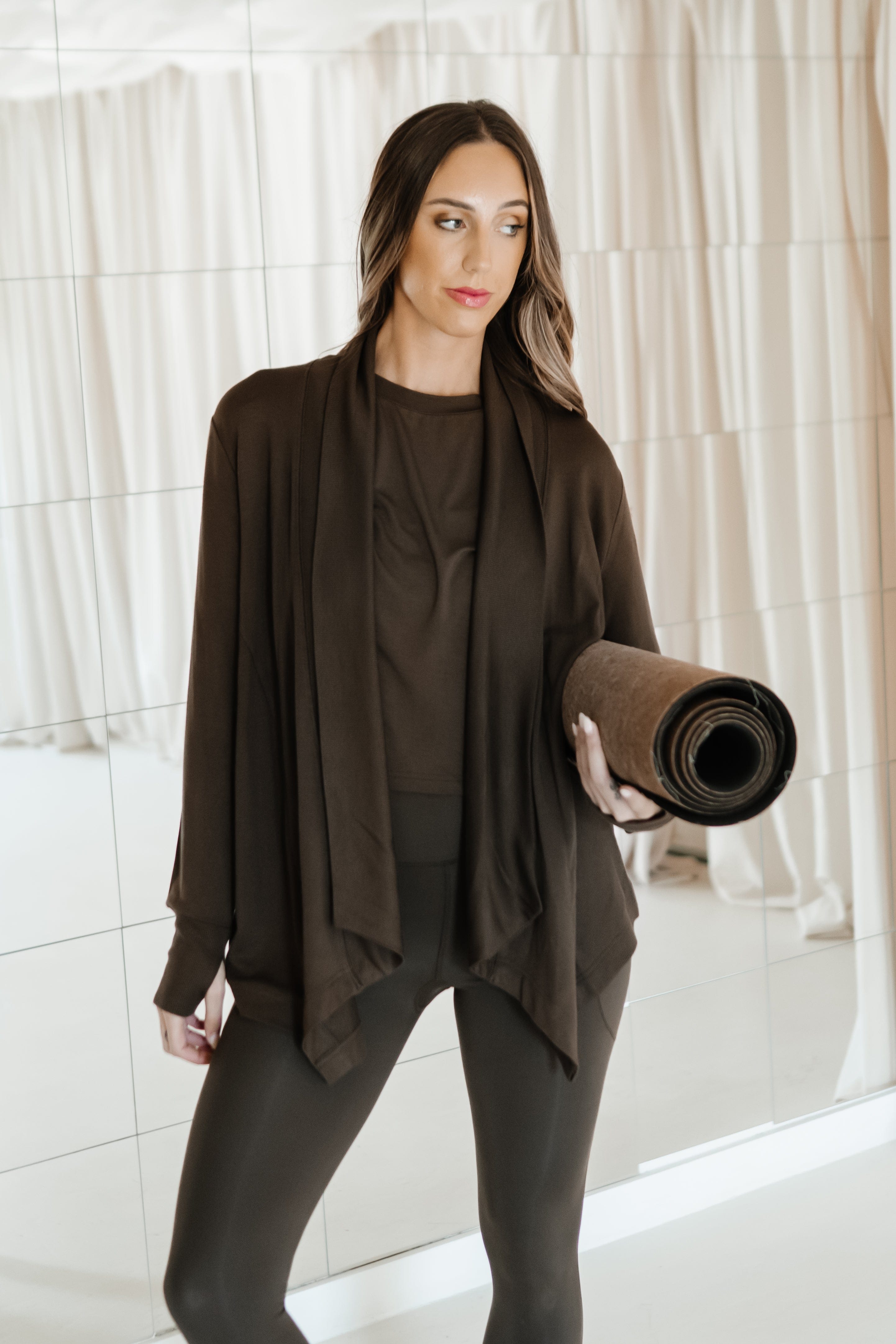 Female holding a yoga mat wearing the Bamboo Flex Women’s Leggings in Espresso and matching short sleeve tee and french terry wrap top