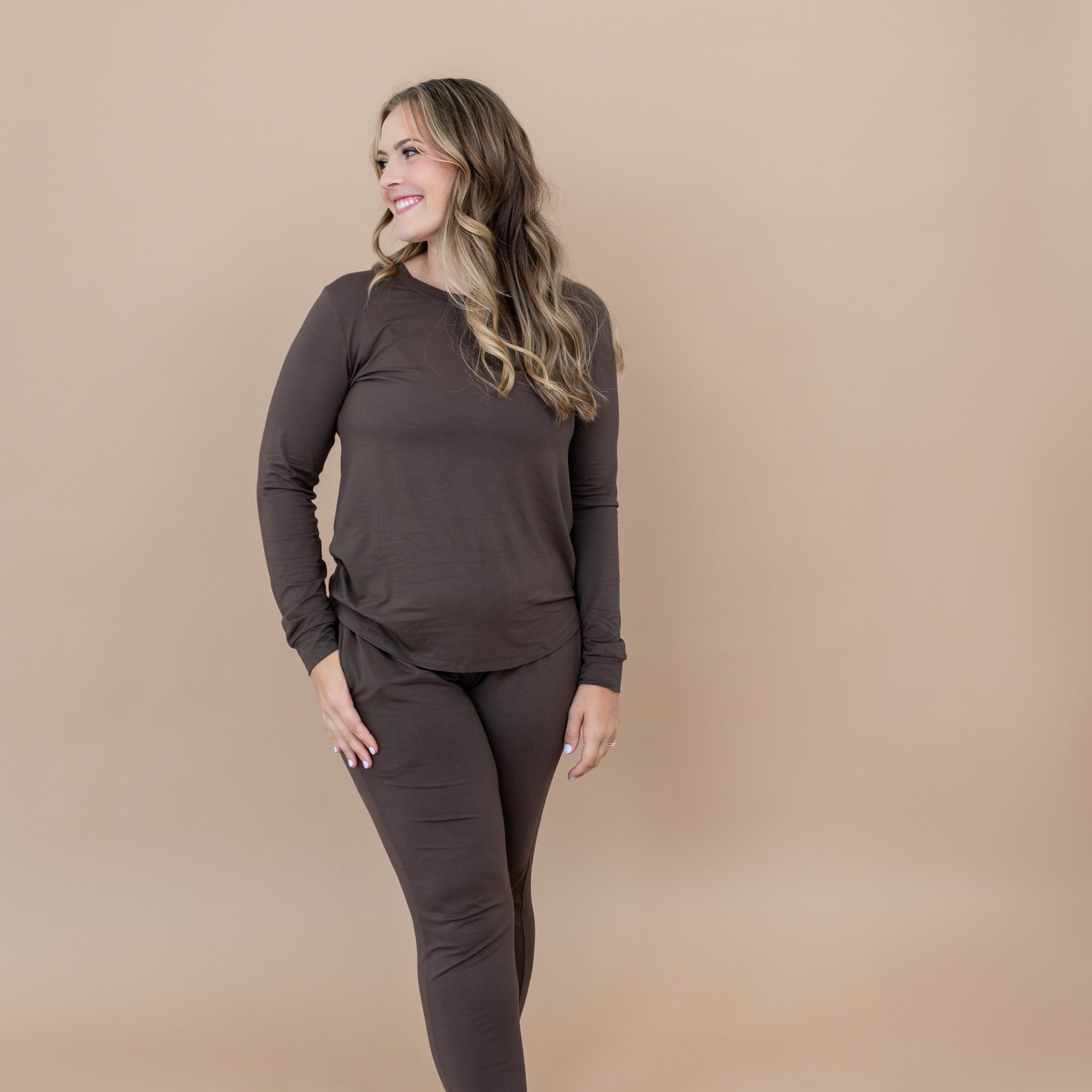 Smiling female model with one hand in Women's Jogger Pajama Set in Espresso pants pocket looking off to the side