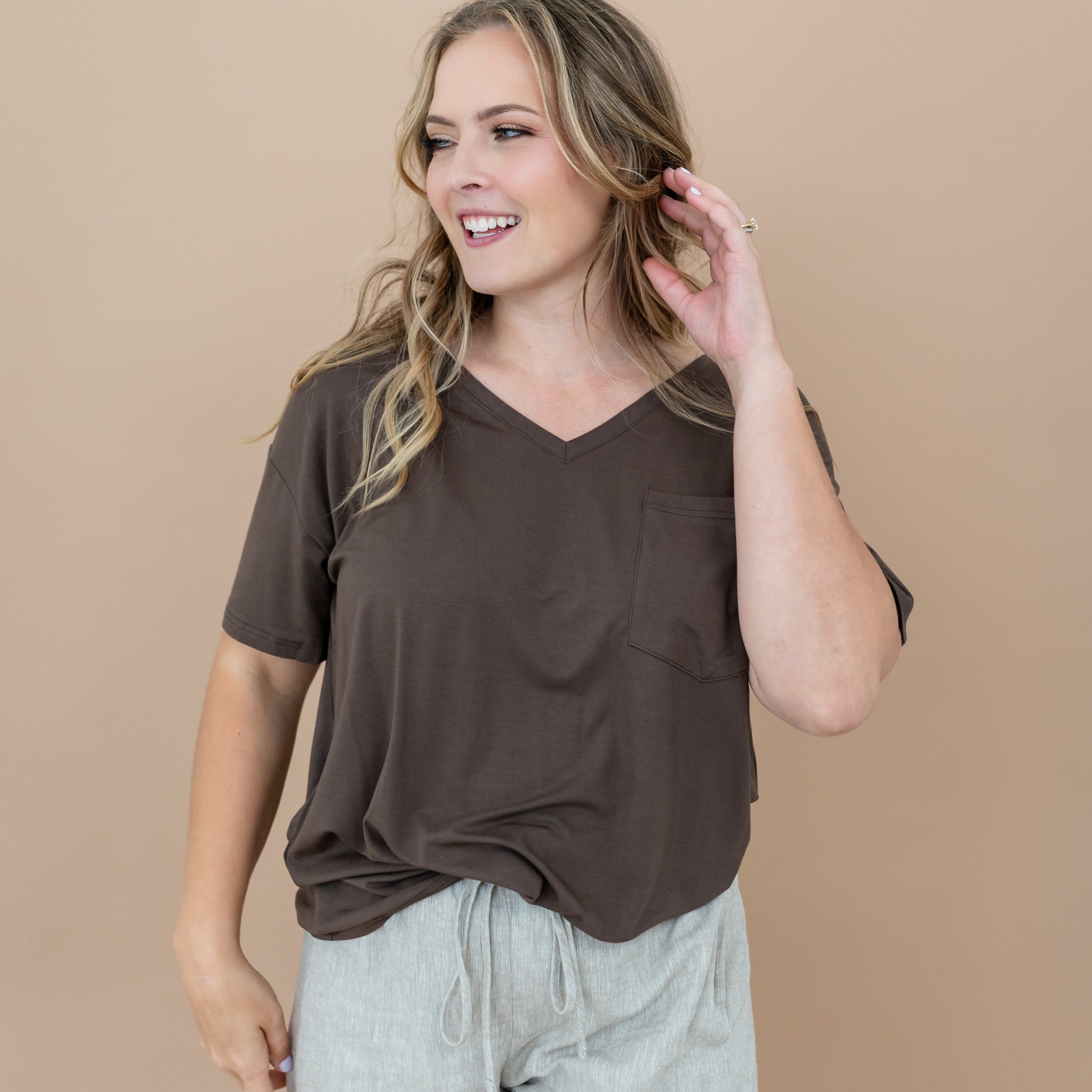 Female looking off to the side with her hand in her hair wearing the Women’s Relaxed Fit V-Neck in Espresso