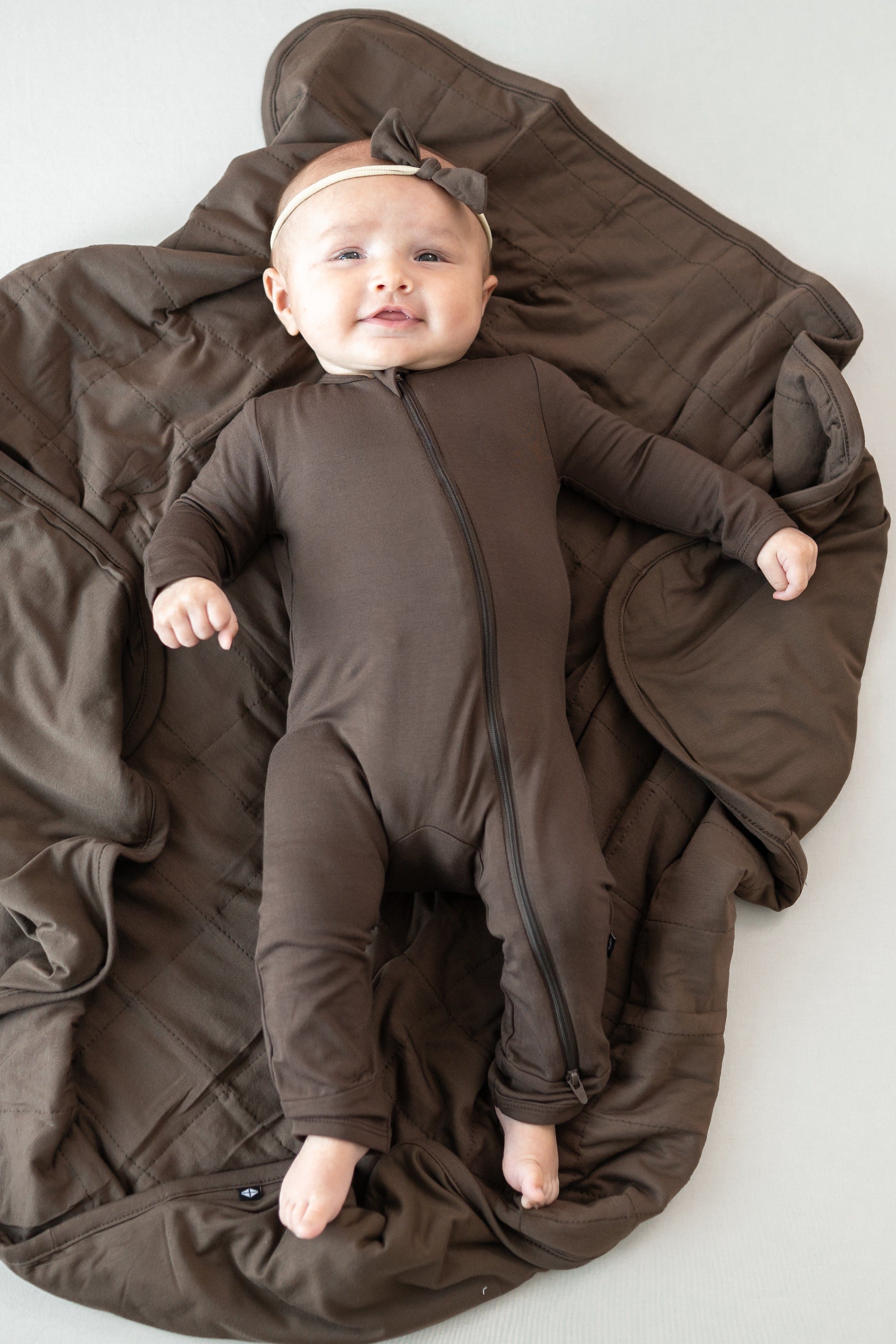 Infant laying on a Baby Blanket in Espresso 1.0 wearing a matching zippered romper