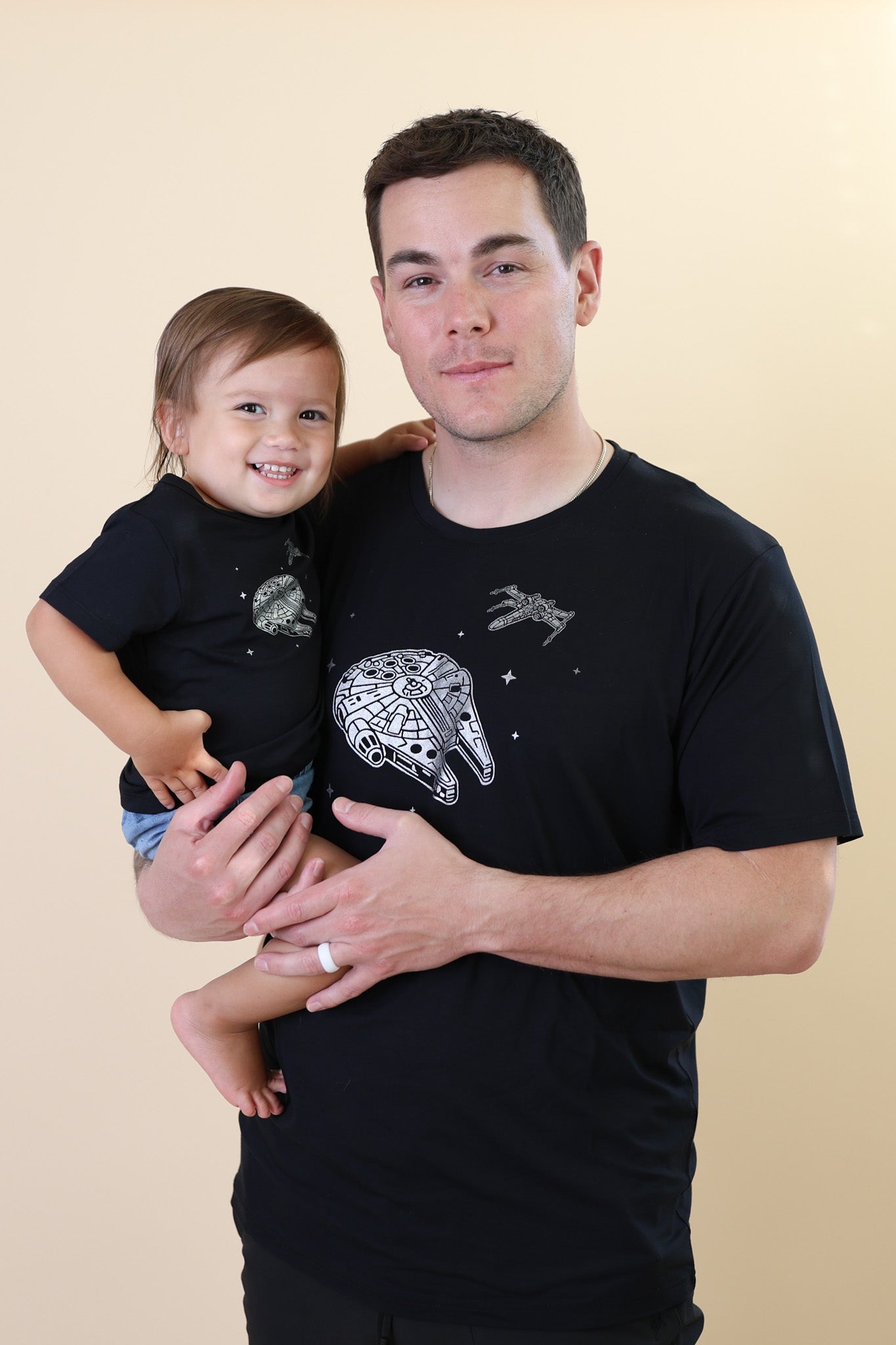 Father holding his son both matching in Millennium Falcon™ Tees