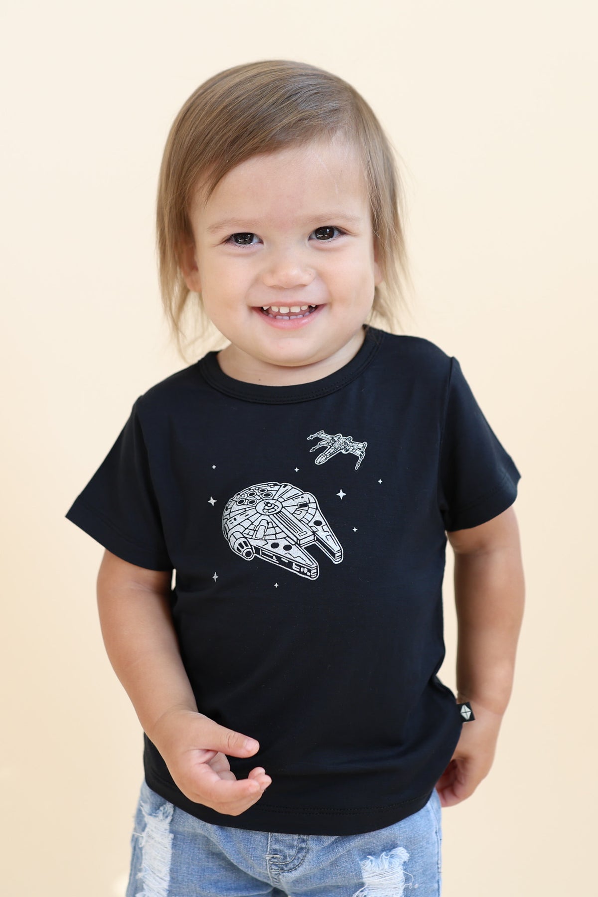 Young boy modeling the Toddler Basic Tee in Millennium Falcon™ paired with light wash denim