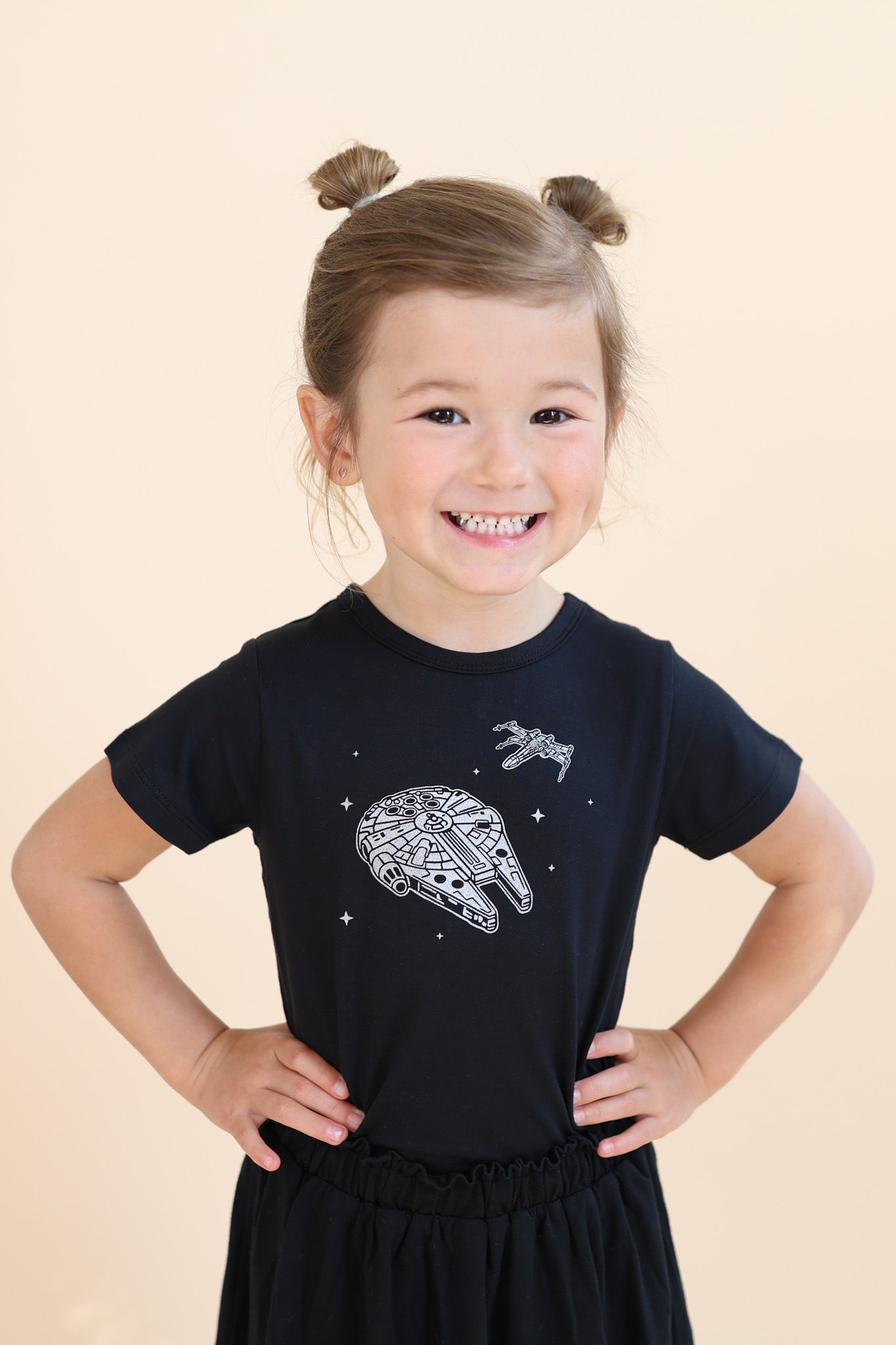 Young girl modeling the Toddler Basic Tee in Millennium Falcon™ paired with a black skort