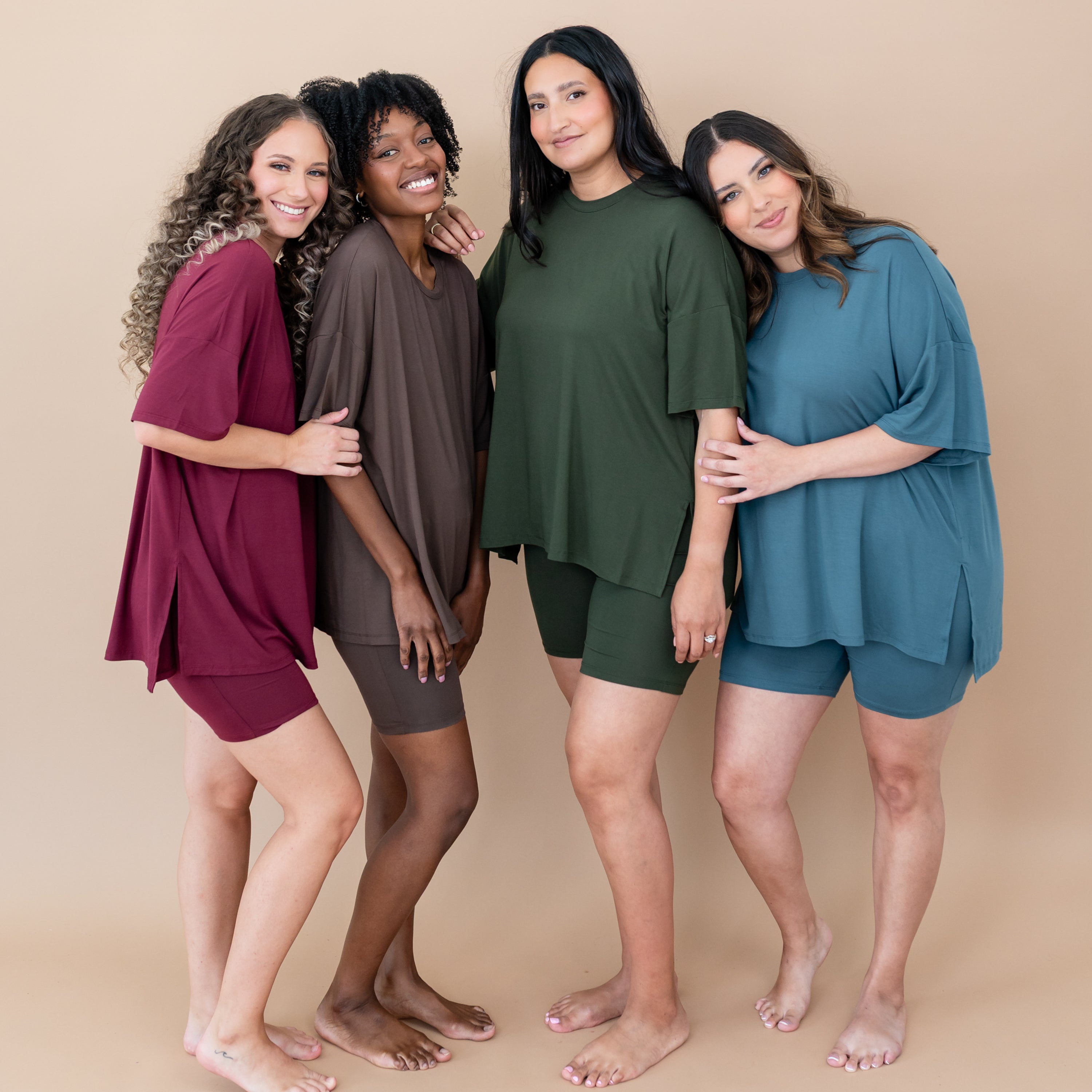 Four women wearing matching bamboo biker short sets in various colors on a beige background