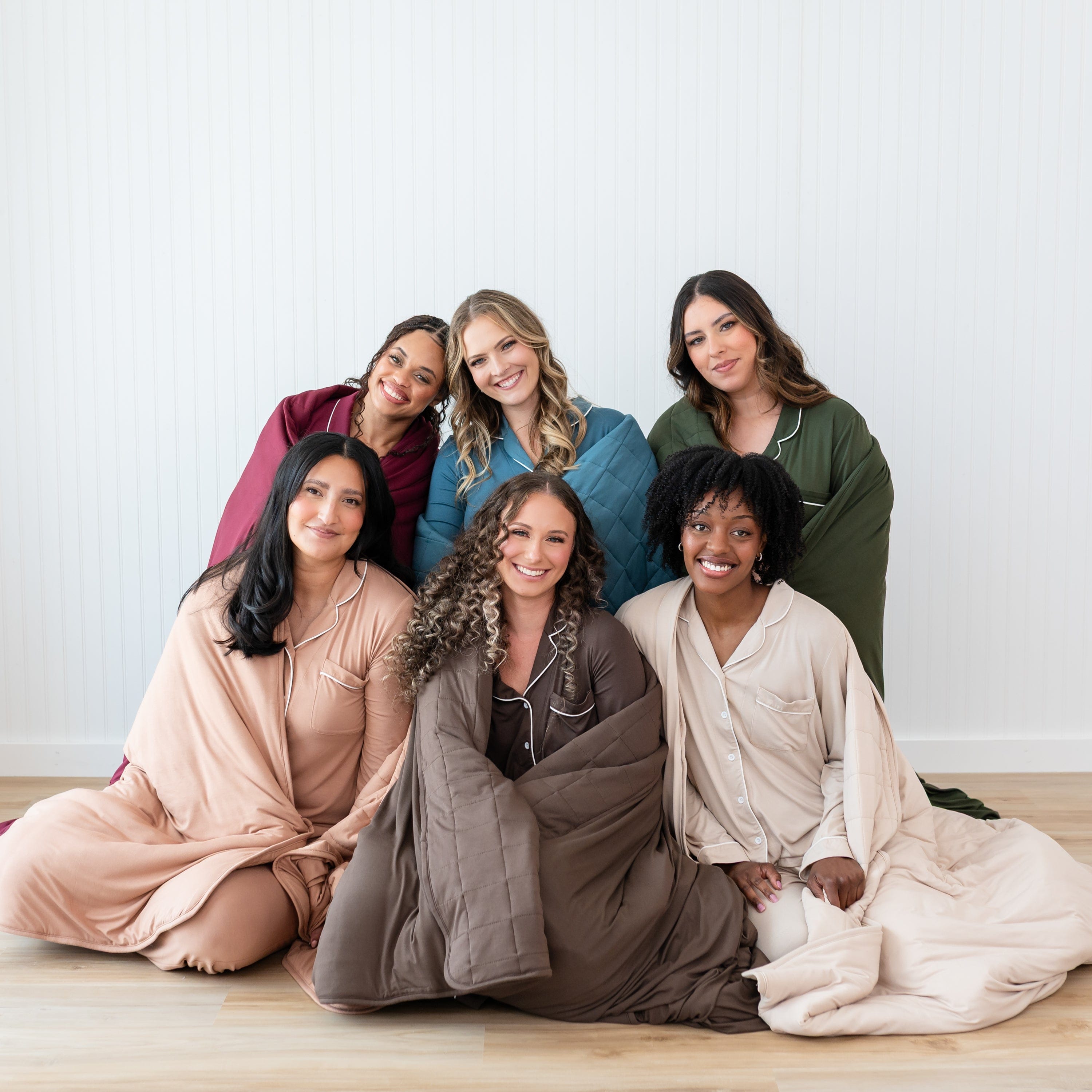 6 female models sitting around one another wearing Adult Quilted Blankets in 2.5 around them in Fall colors
