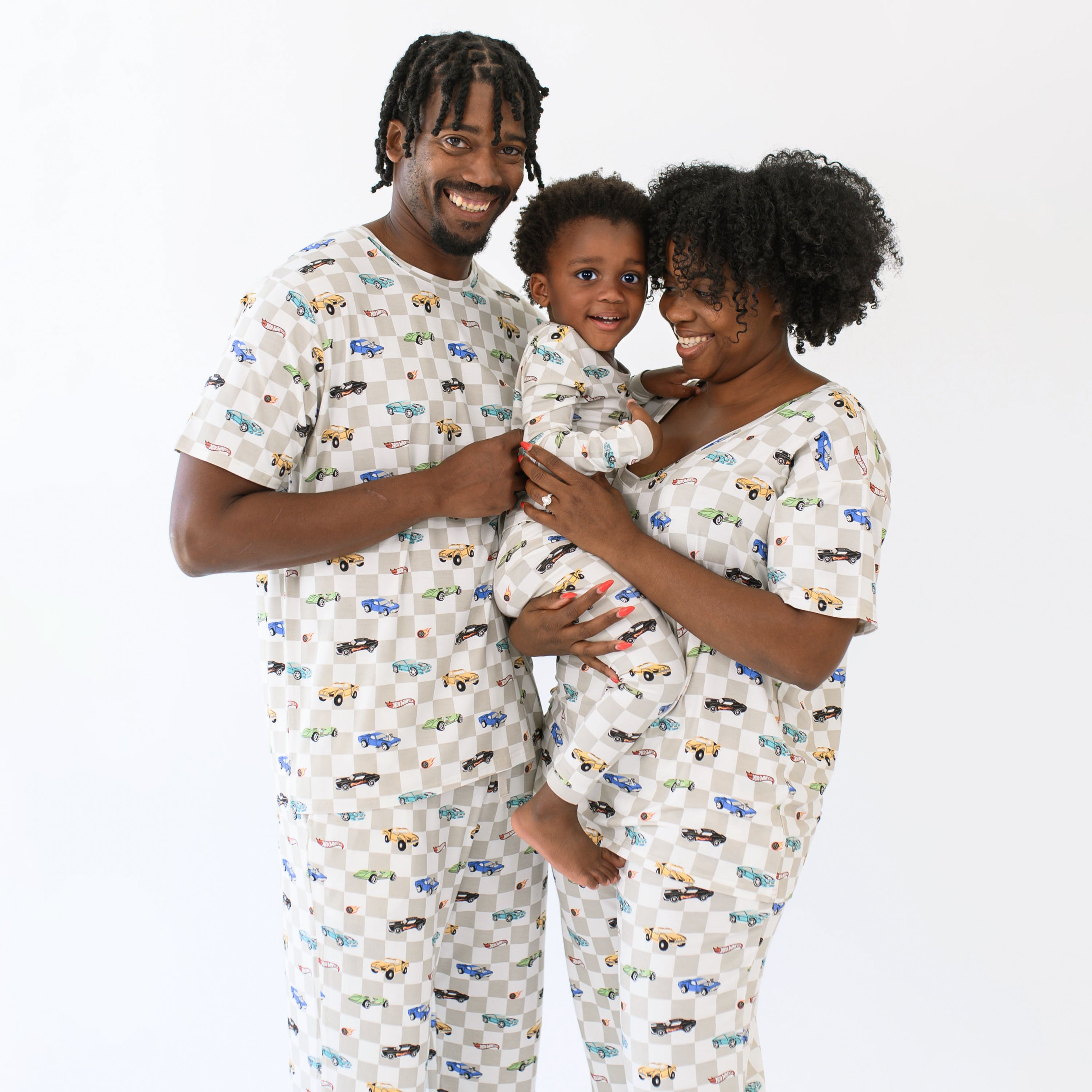 Family matching in Fast and Fierce. Father wearing the Men's Crew Neck Tee in Fast and Fierce standing beside his wife wearing the women's v-neck and women's lounge pants holding their son who is in long sleeve toddler pajamas