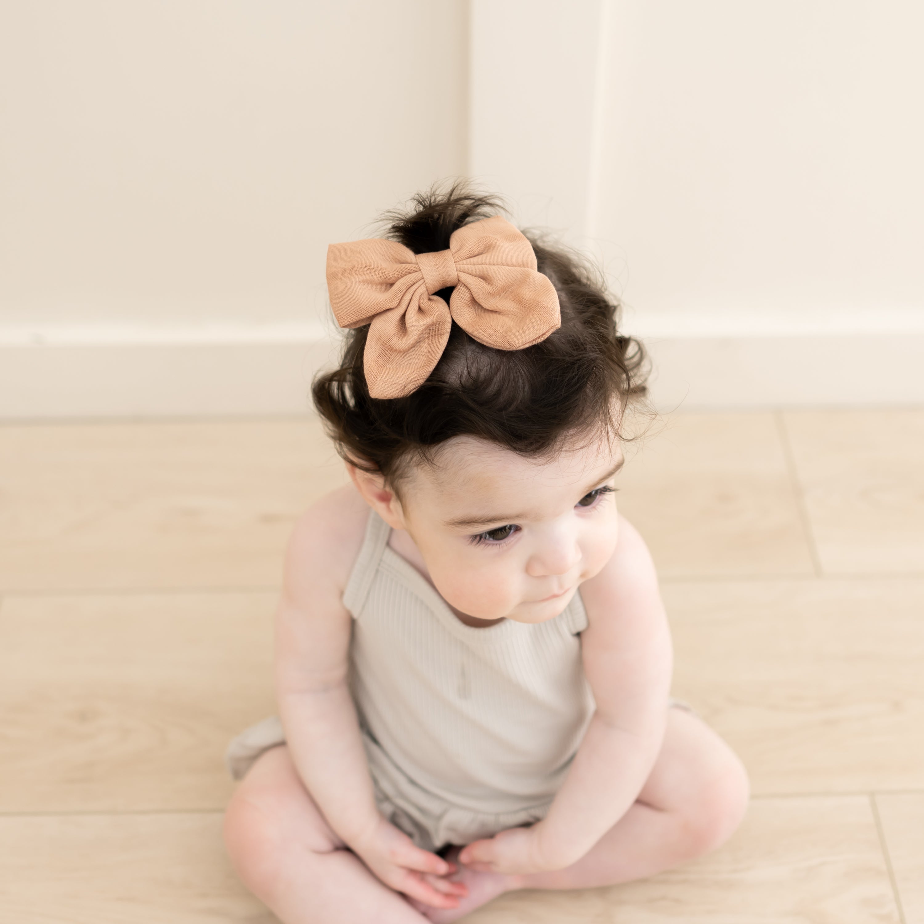 Baby wearing Bamboo Muslin Bow Clip in Fawn with Oat Bodysuit