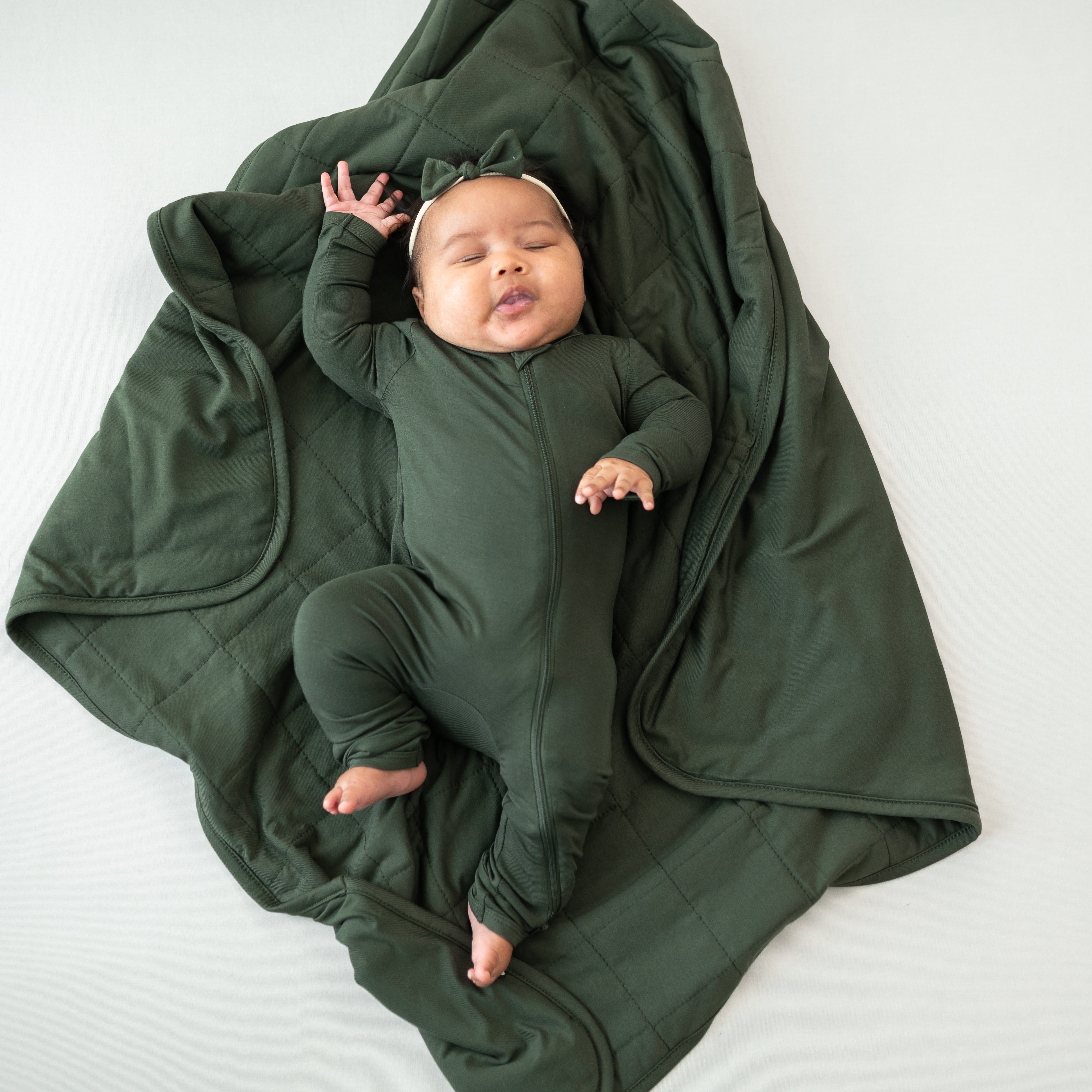 Baby wearing Fir Zippered Romper laying on Baby Blanket in Fir 1.0