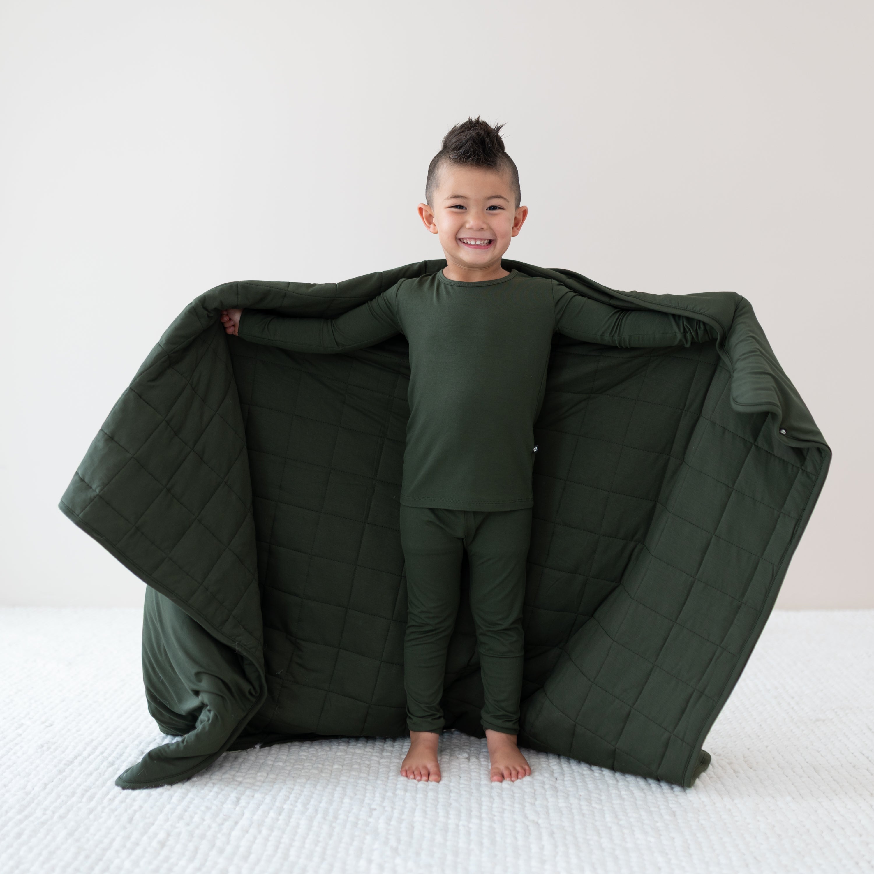 Child wearing a size 2T Fir Pajamas holding a Toddler Blanket in Fir 2.5
