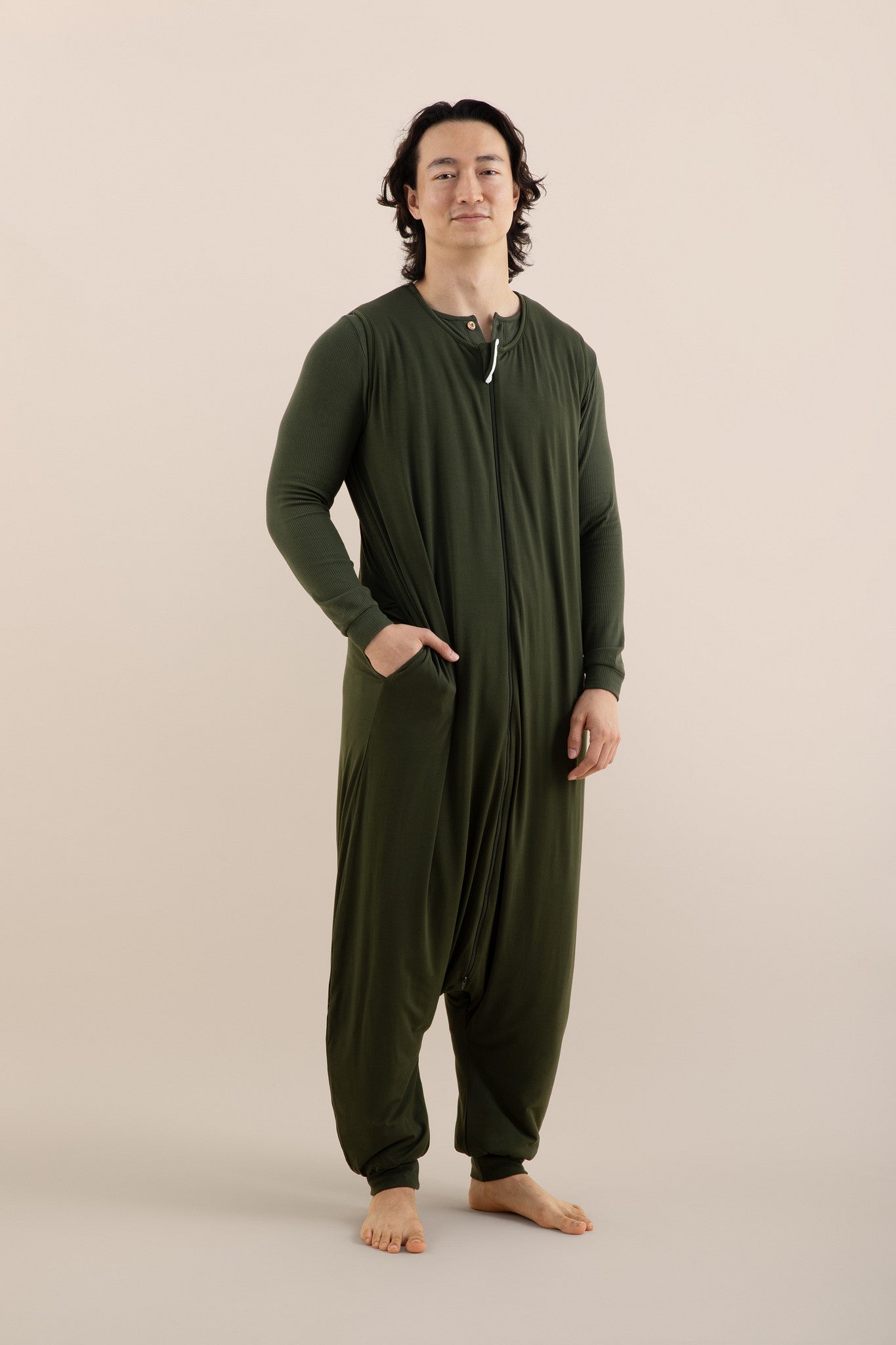 Male model wearing the Adult Sleep Bag Walker in Fir with one hand in the pocket