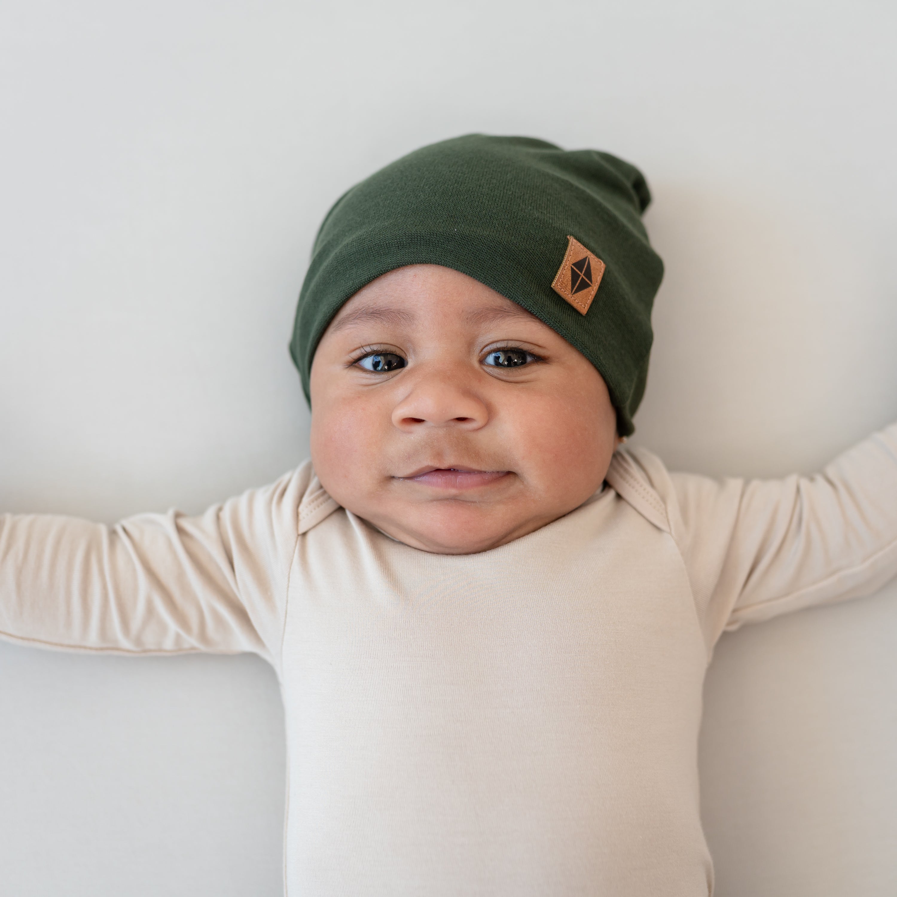 Baby wearing Bamboo Jersey Beanie in Fir with Bisque long sleeve bodysuit
