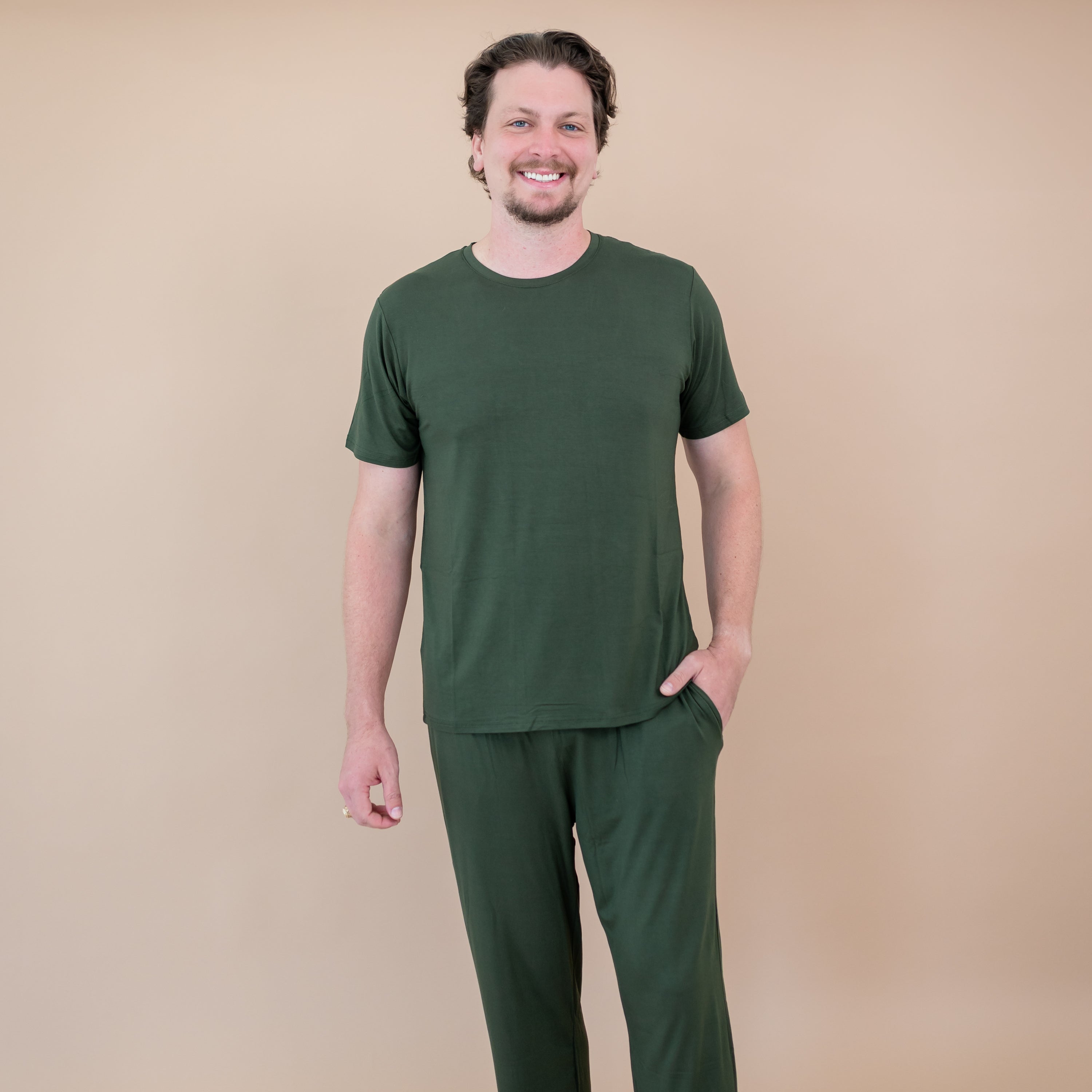 Man wearing a green t-shirt and pants against a beige background