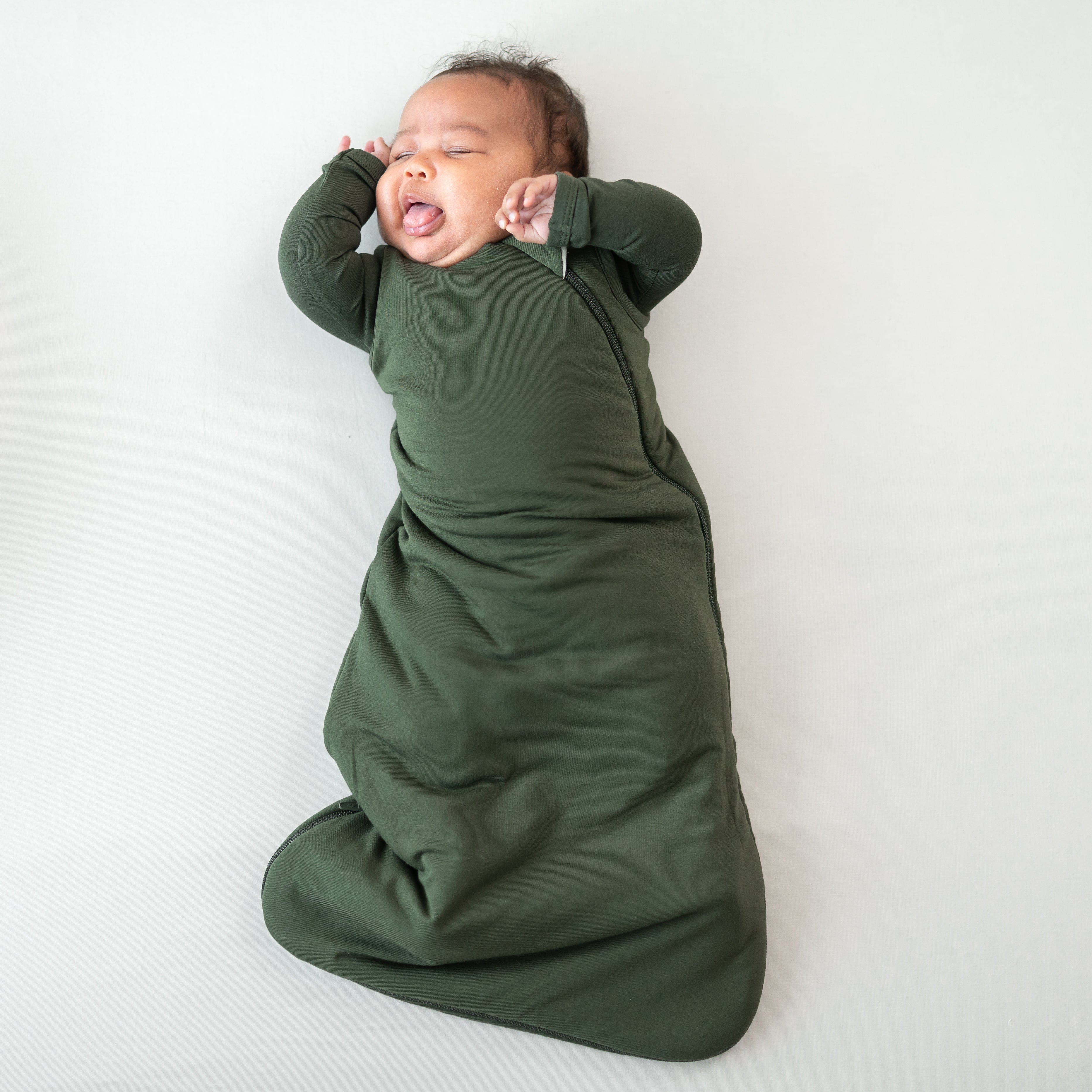Baby asleep in Sleep Bag in Fir 1.0 laying on a white background