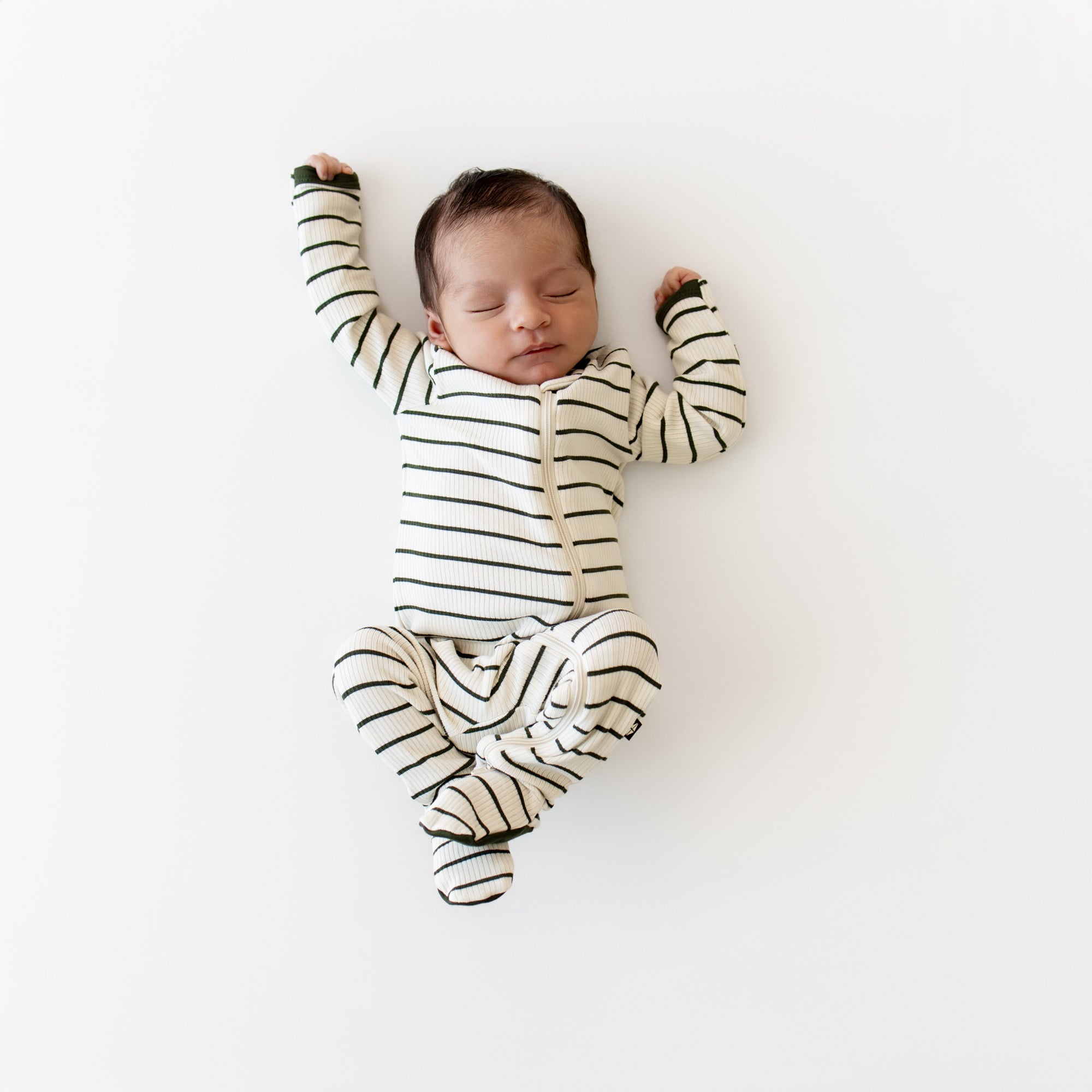 Sleeping newborn laying stretched out wearing the Ribbed Zipper Footie in Fir Stripe