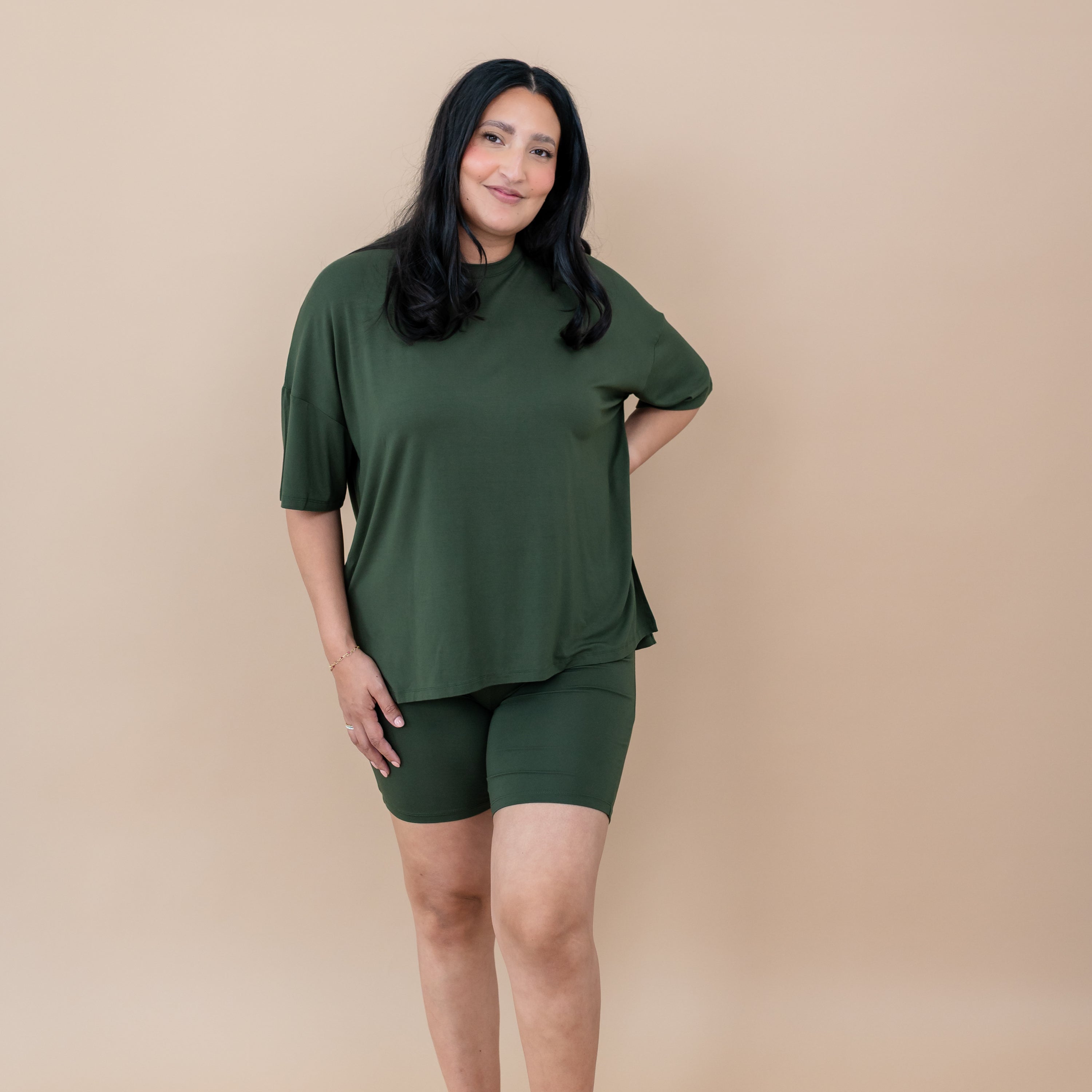 Woman wearing a bamboo biker set in a deep green color on a beige background