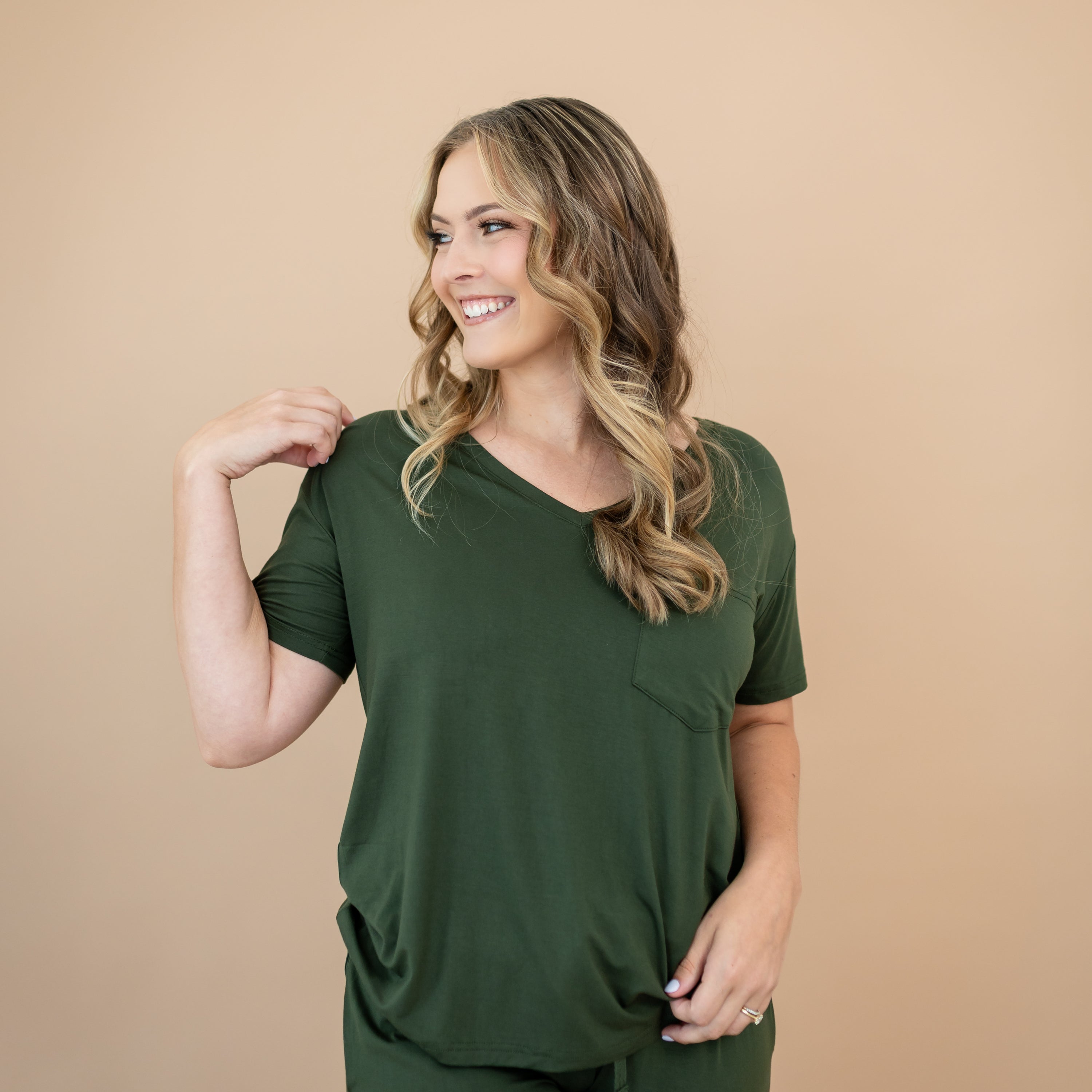 Woman wearing a green v-neck against a beige background
