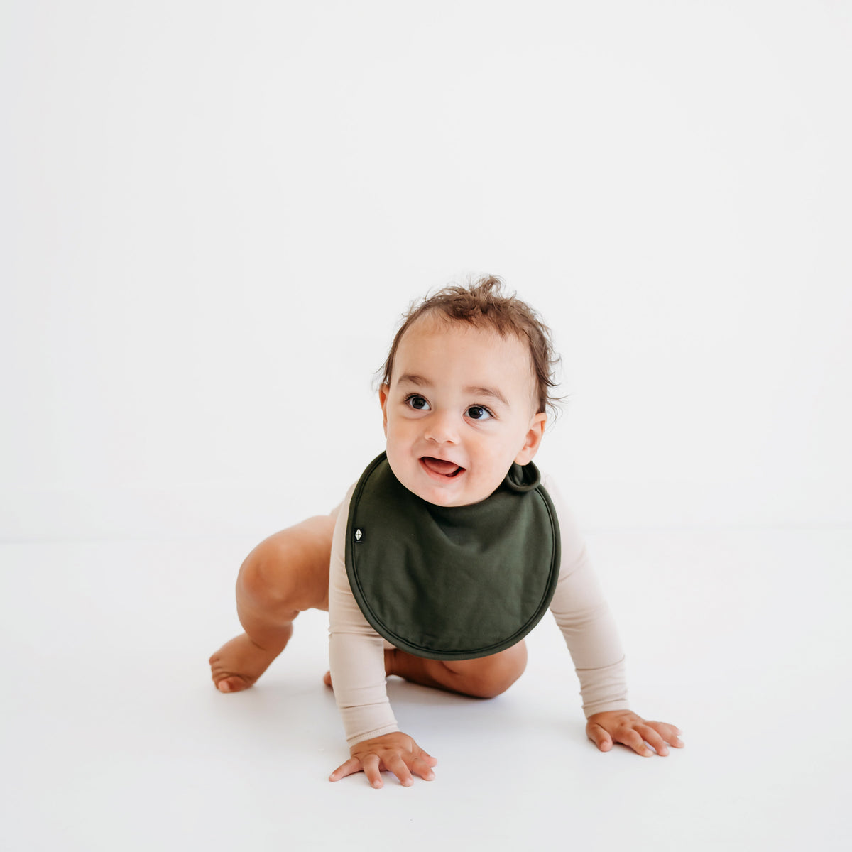 Baby crawling wearing Cushy Bib in Fir