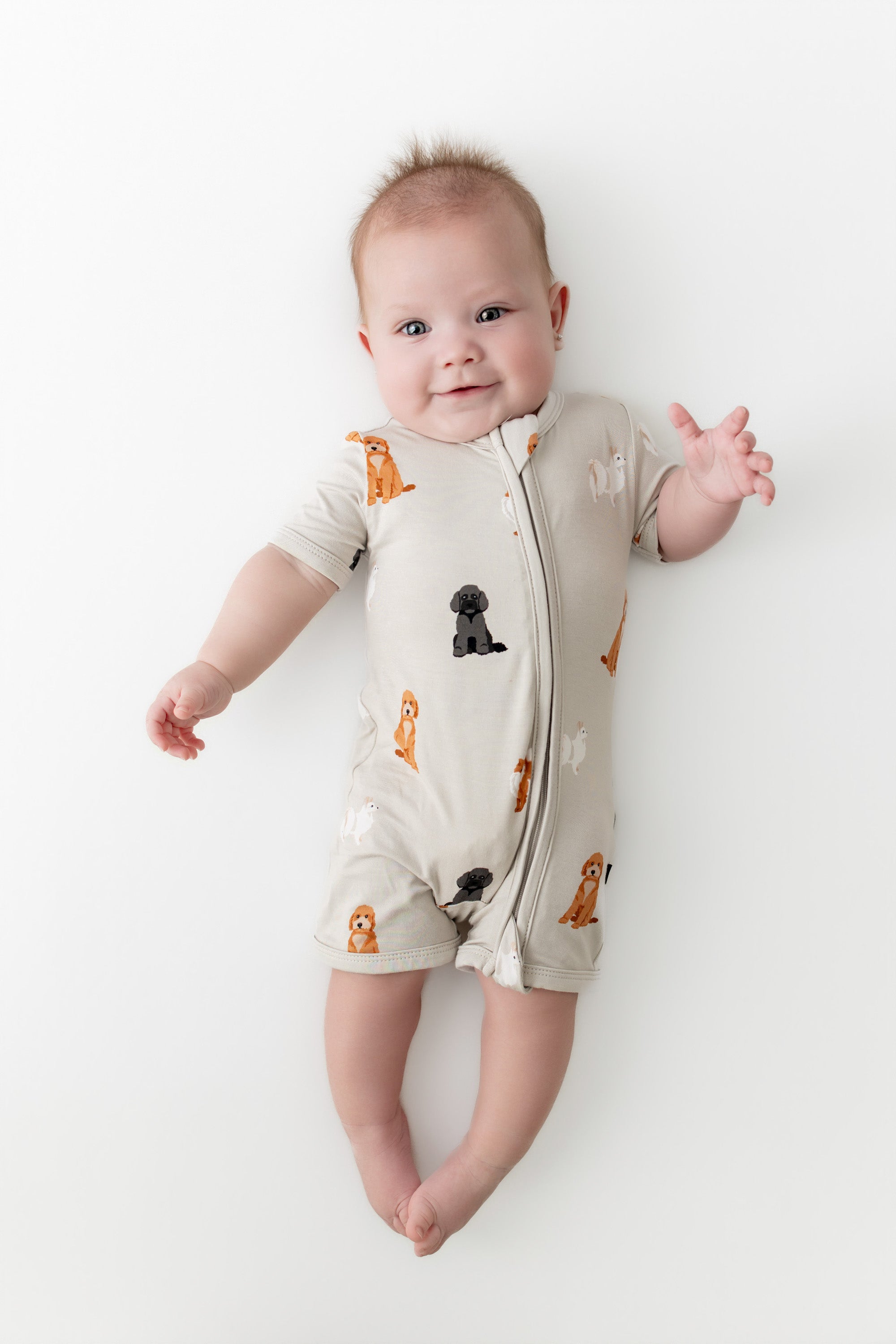 Baby wearing a onesie with dog prints on a white background