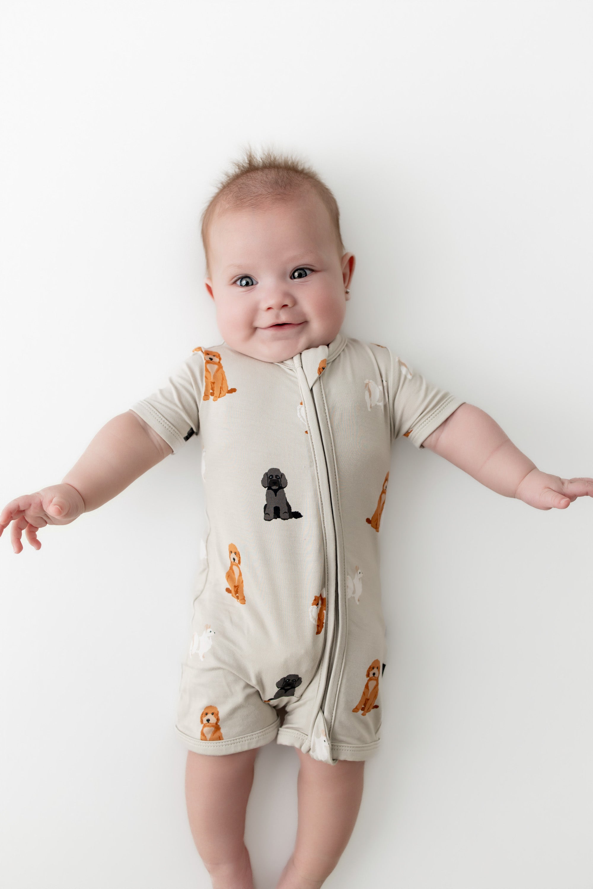 Baby wearing a dog patterned onesie on a white background