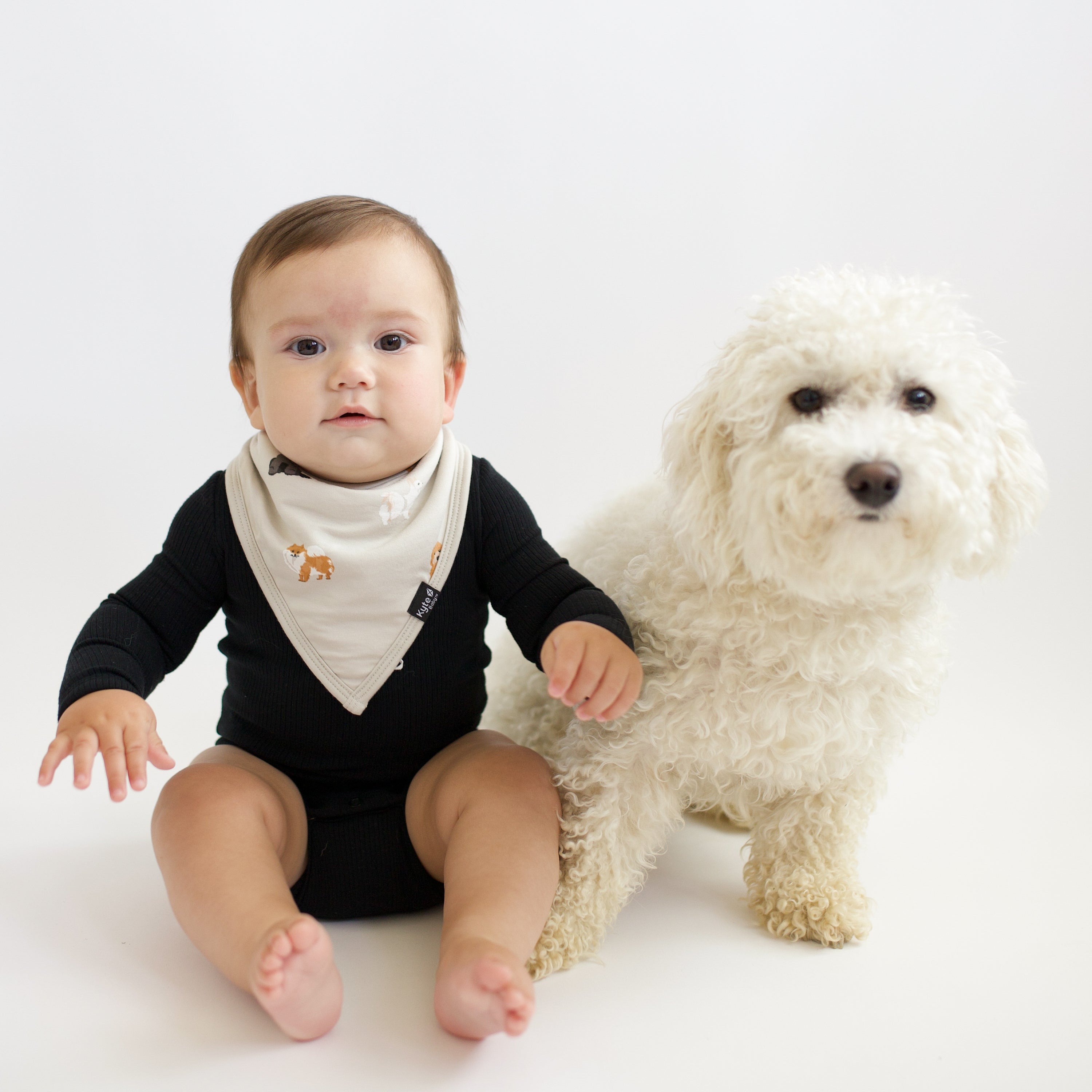 Baby wearing Bib in Fluffy Dog and Midnight Long Sleeve Bodysuit next to real dog