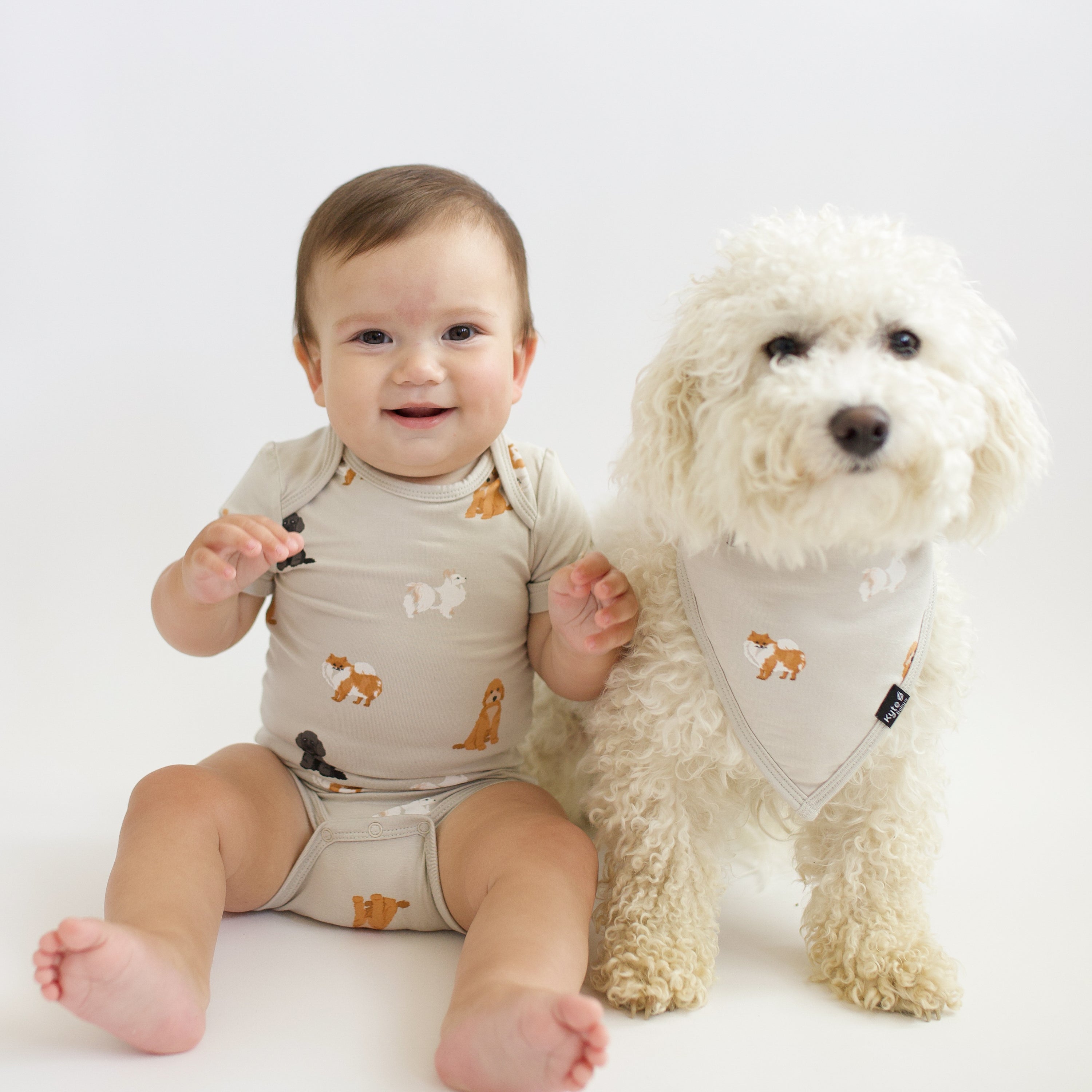 Baby wearing Bodysuit in Fluffy Dog next to a real dog