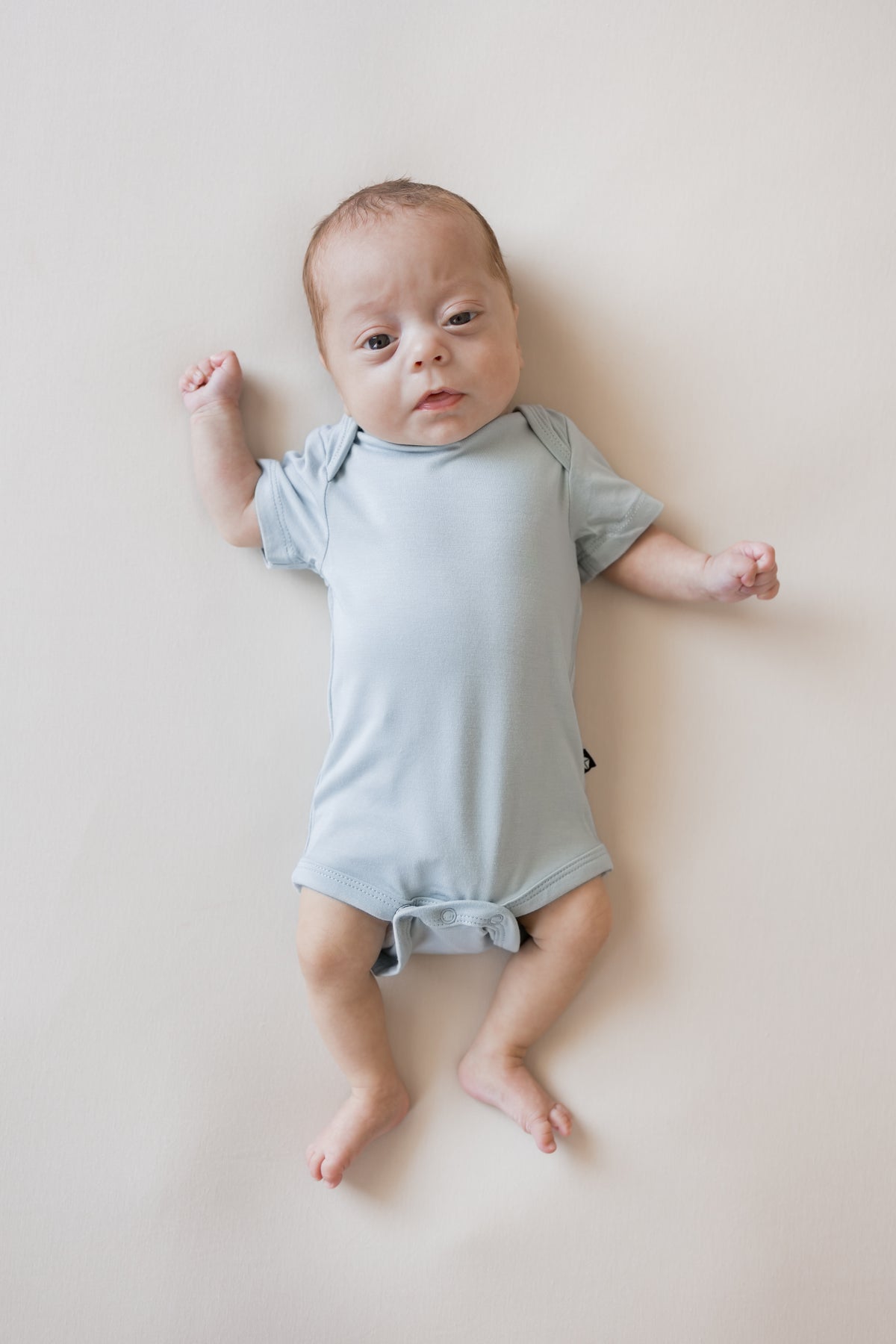 Baby wearing Bodysuit in Fog color on a beige background