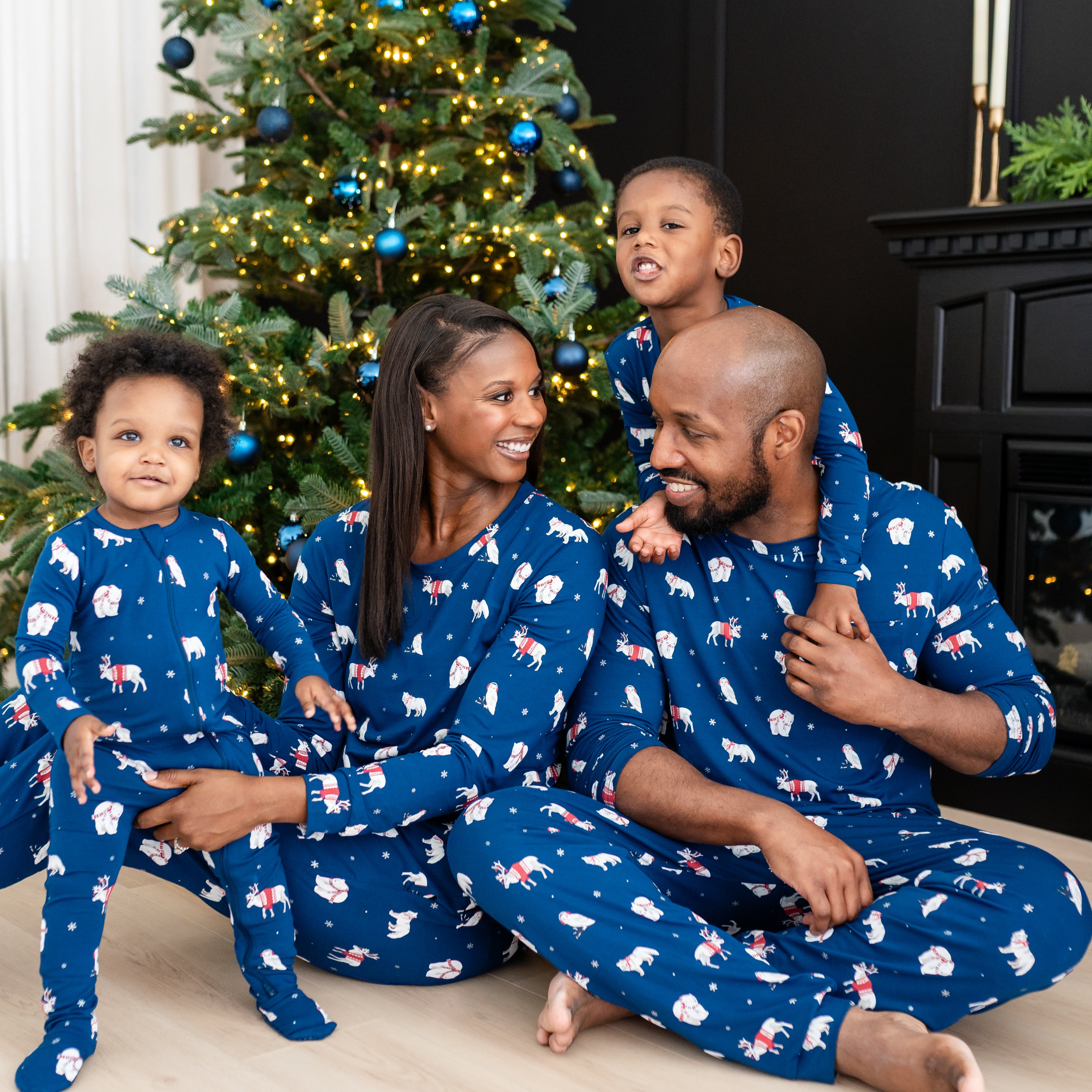 Family of four sitting on the floor matching in Frosty Friends pajama sets