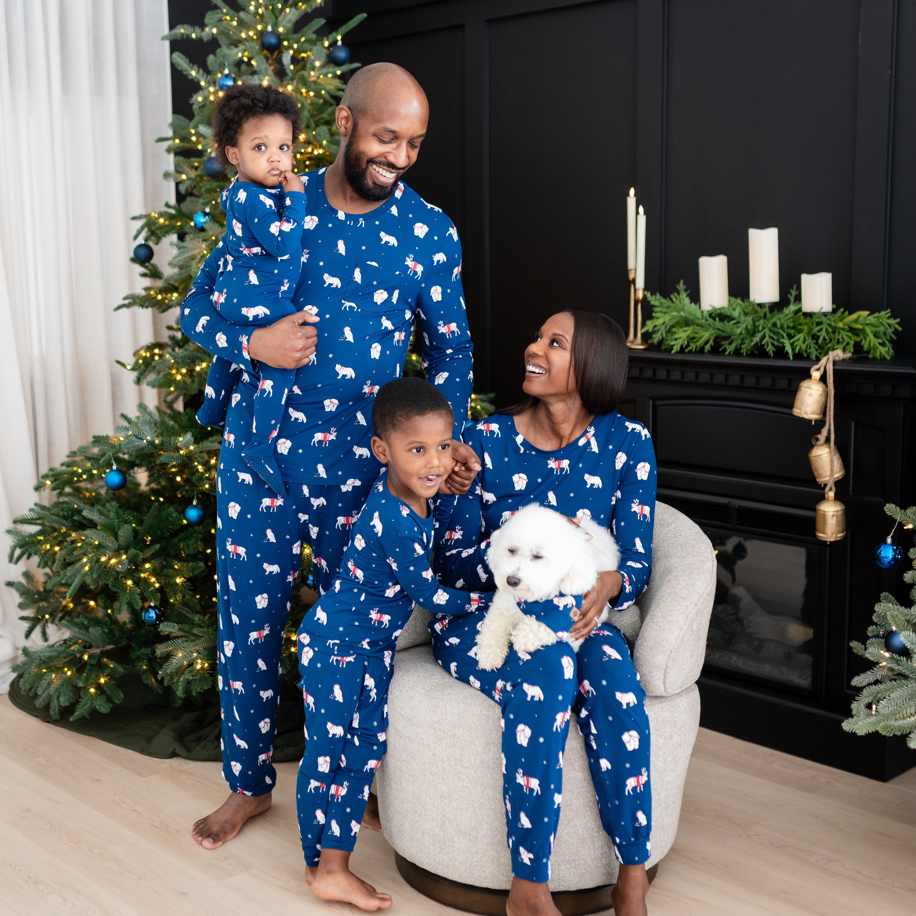 Family of for wearing the holiday print in Frosty Friends pajama set with a small white dog wearing the dog bandana