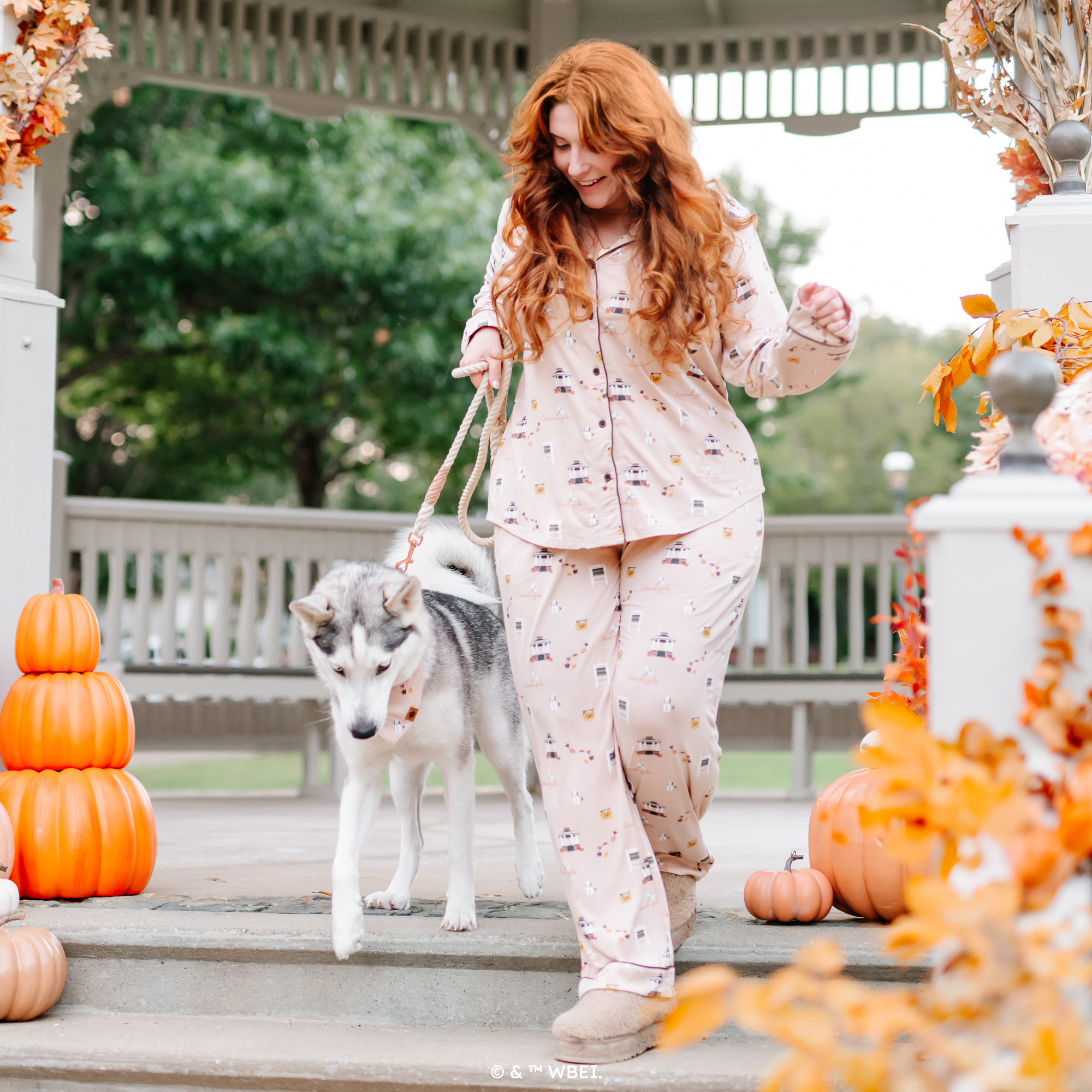 Female model wearing the Long-Sleeved Women's Pajama Set in Gilmore Girls walking her dog down the steps of a gazebo