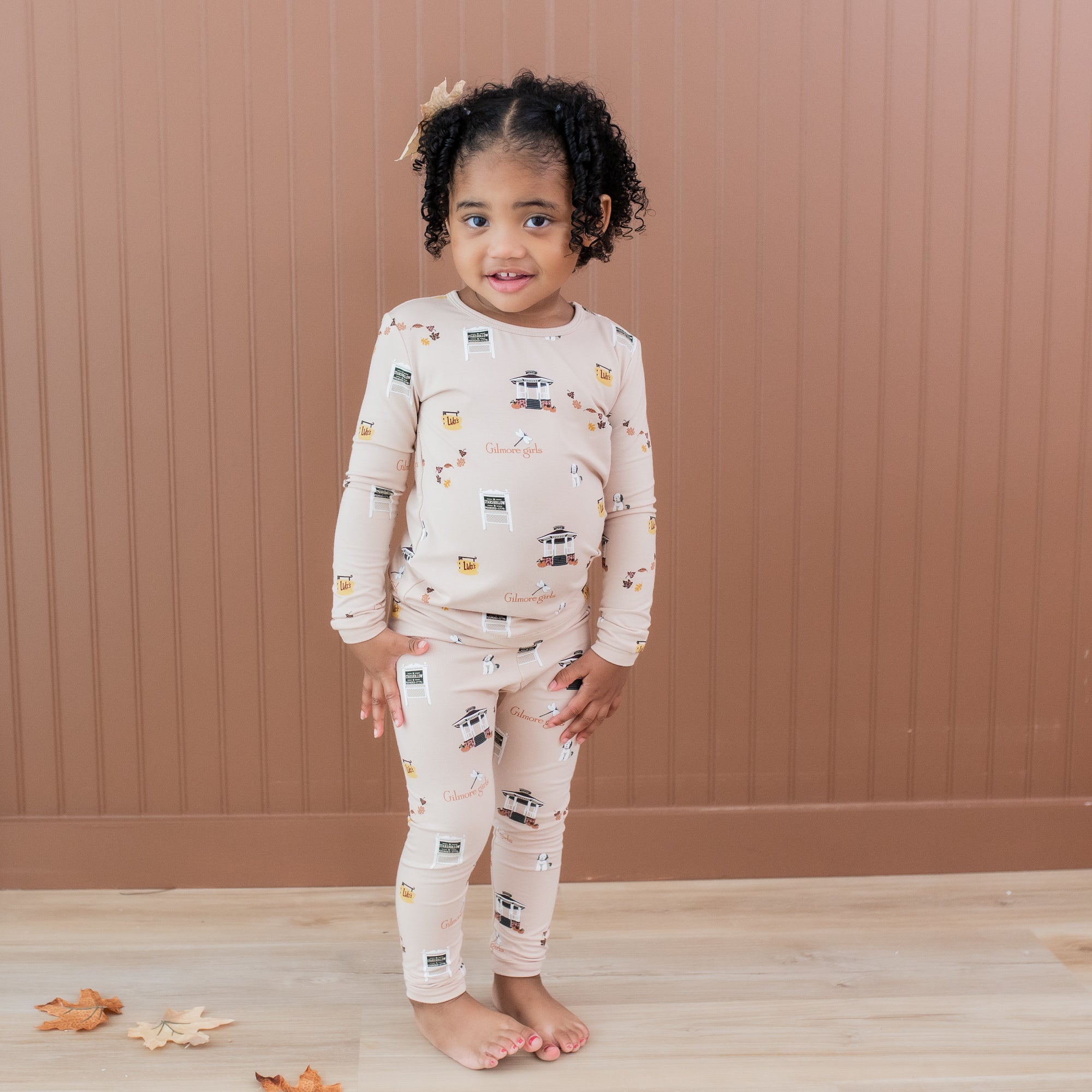 Young girl standing in front of a brown tan paneled wall wearing the Long Sleeve Pajamas in Gilmore Girls