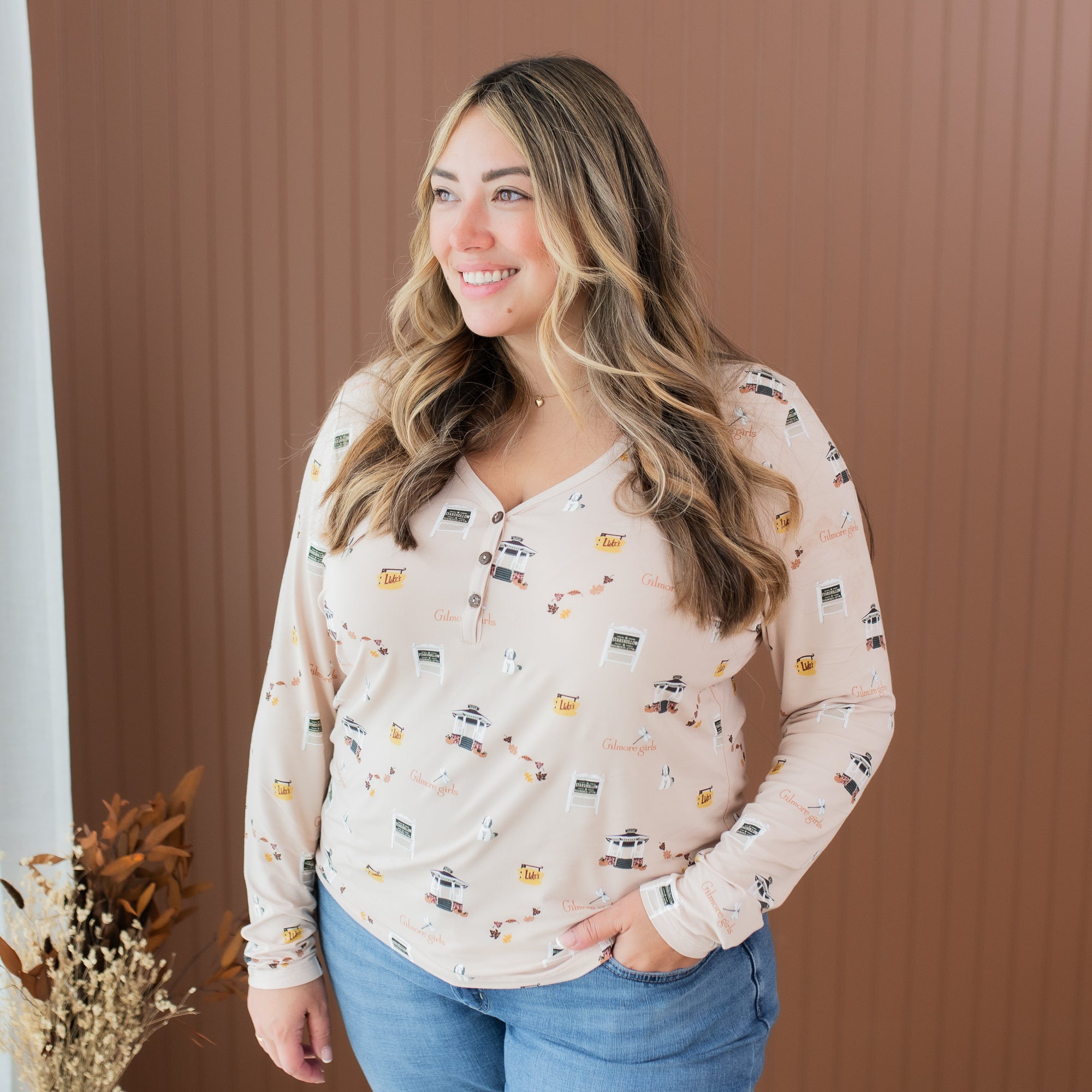 Smiling female model wearing the Women's Long Sleeve Henley Tee in Gilmore Girls with one hand in her jeans pocket